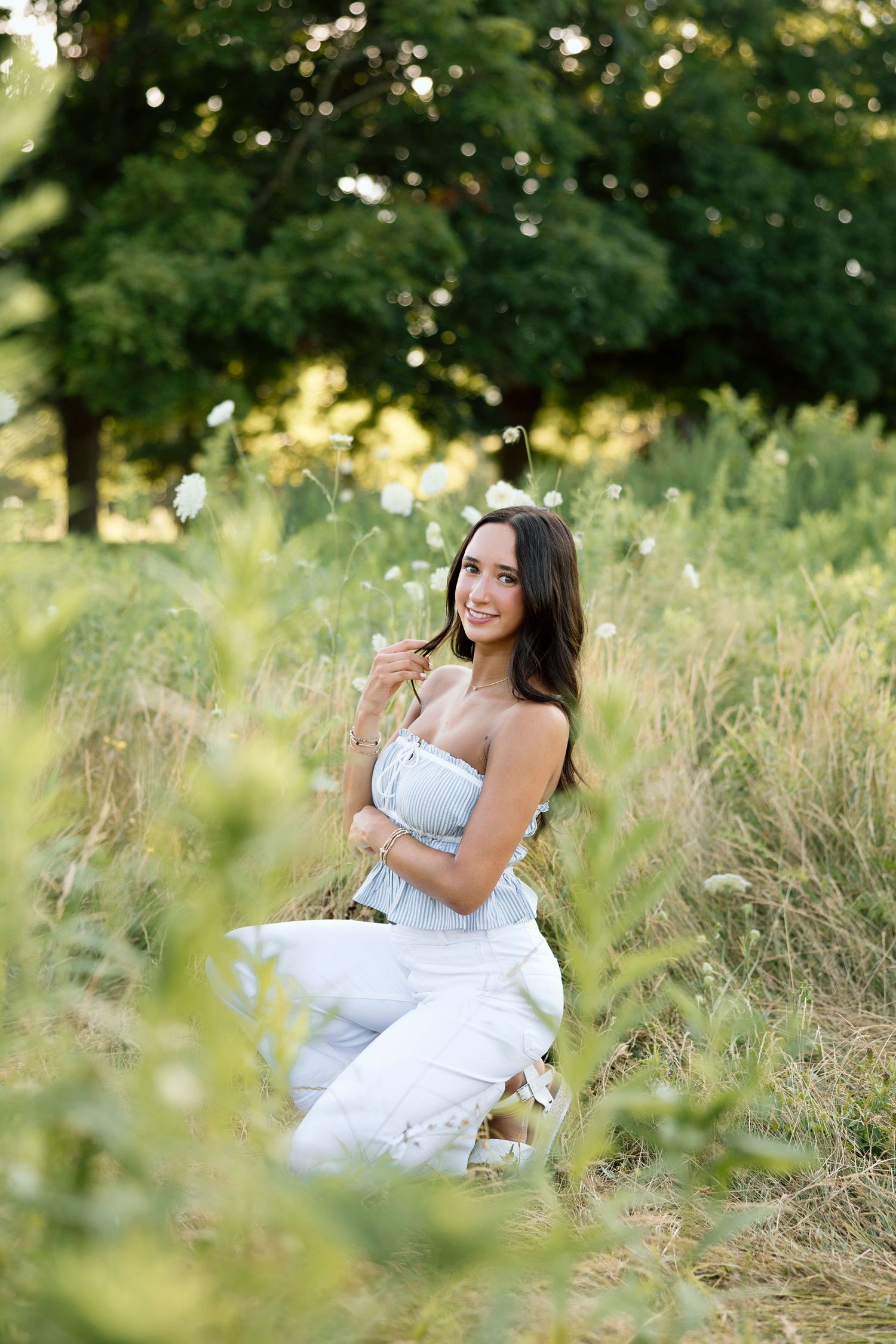 Outdoor senior portrait session in tall grass field during golden hour at Tinker Nature Center, Rochester NY senior portraits.