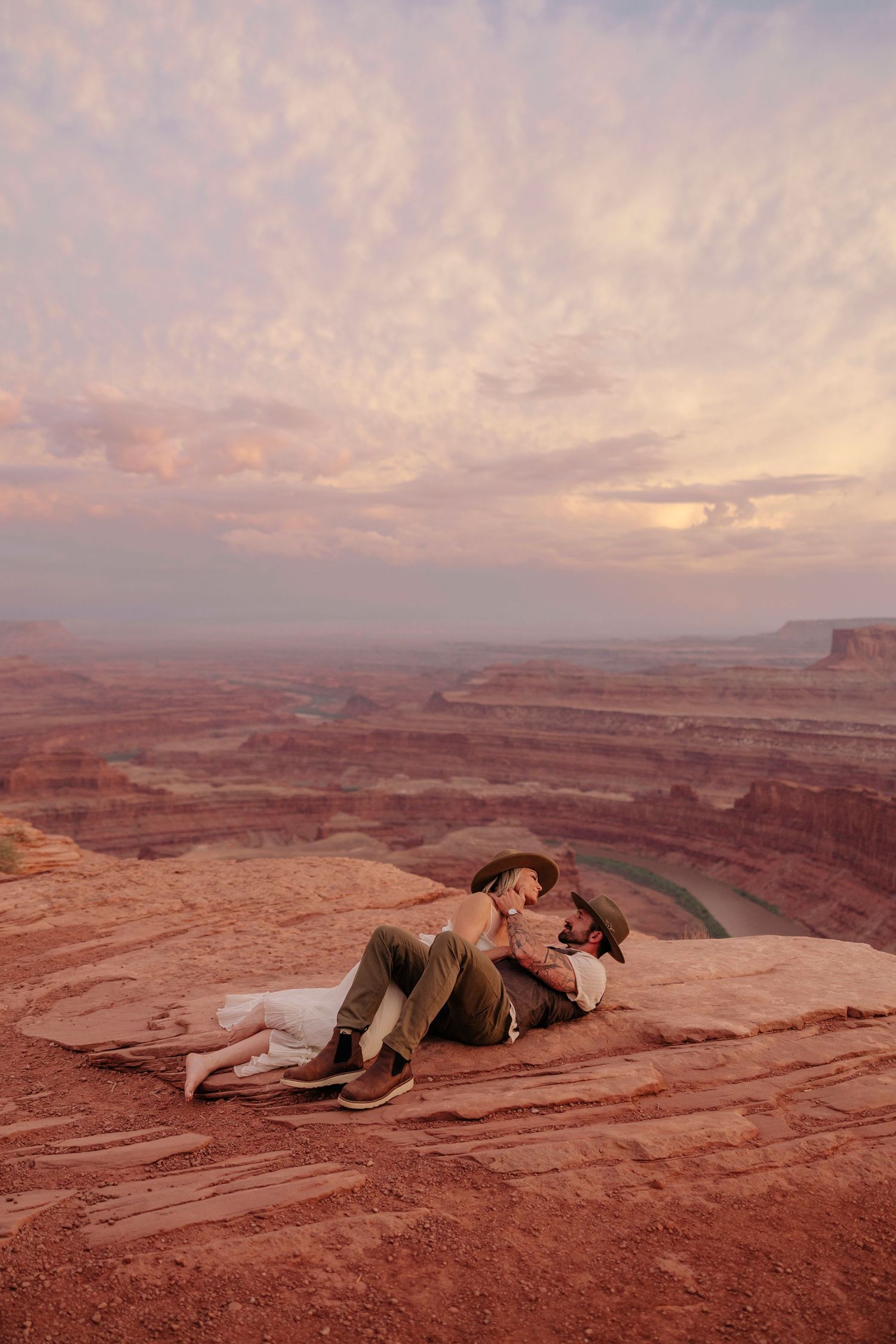 A couple lying on red rock formations at sunset in a desert canyon landscape in Moab Utah elopement.