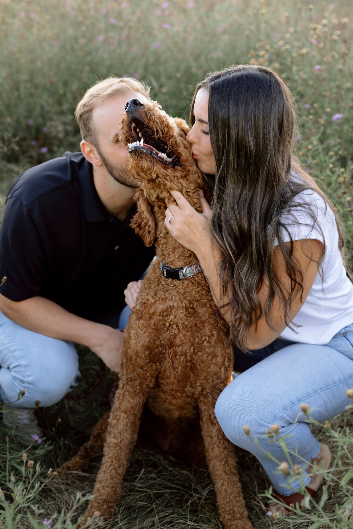Couple shares tender moments with their fluffy brown Golden Doodle in a wildflower field.