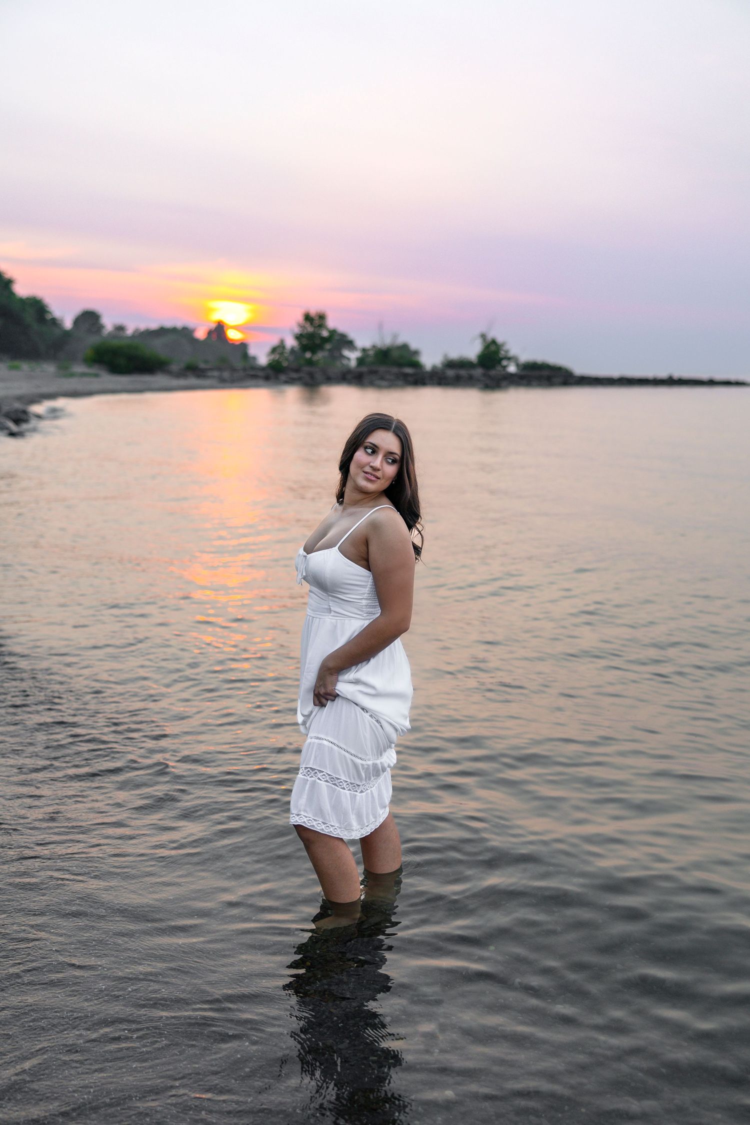Sunset senior photoshoot in Lake Ontario with pink and purple sky reflections at Hamlin Beach, Rochester, NY senior portraits.