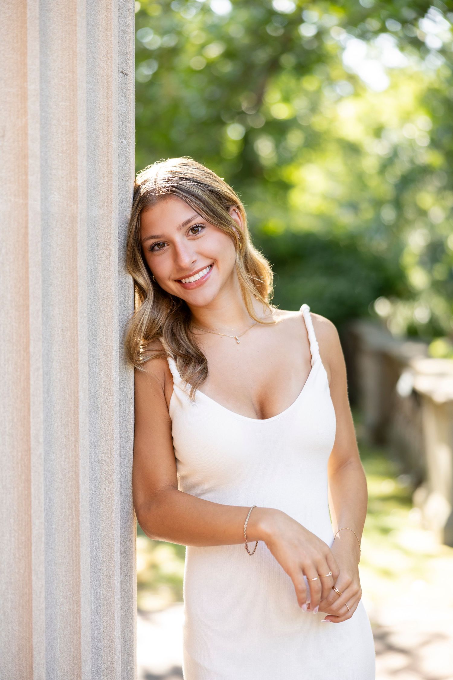 A portrait session between elegant white columns in natural summer lighting at George Eastman House for Rochester NY senior portaits.