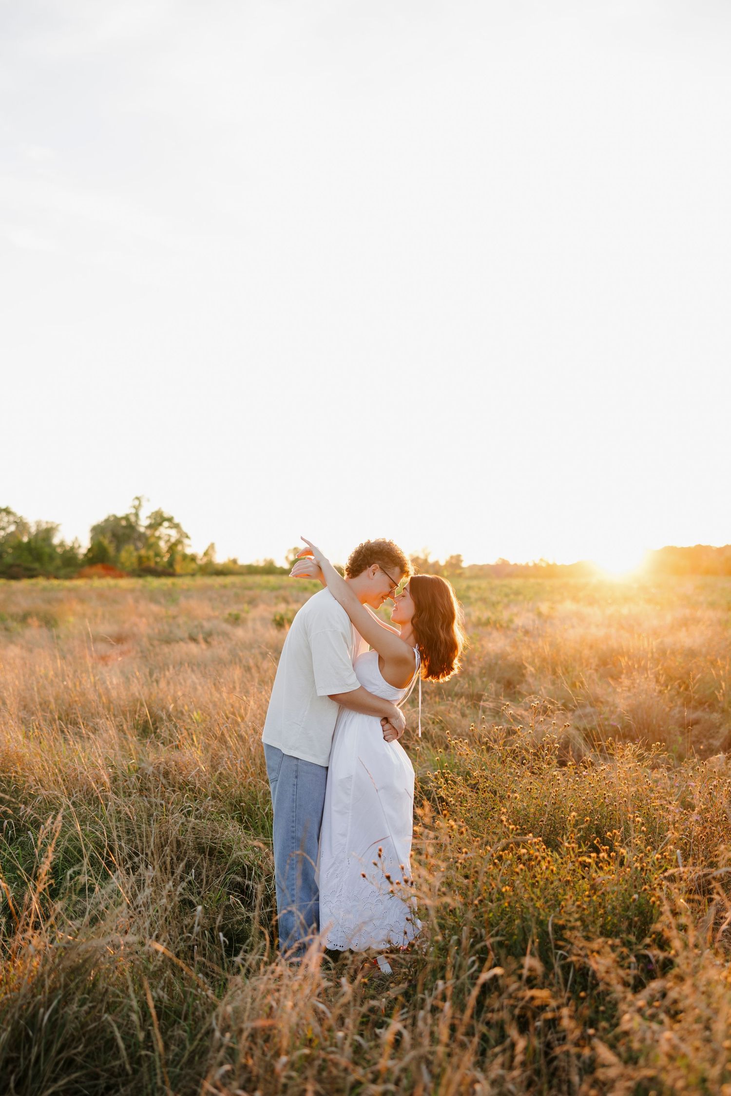 Couple sharing a romantic moment in a sunlit field at golden hour.