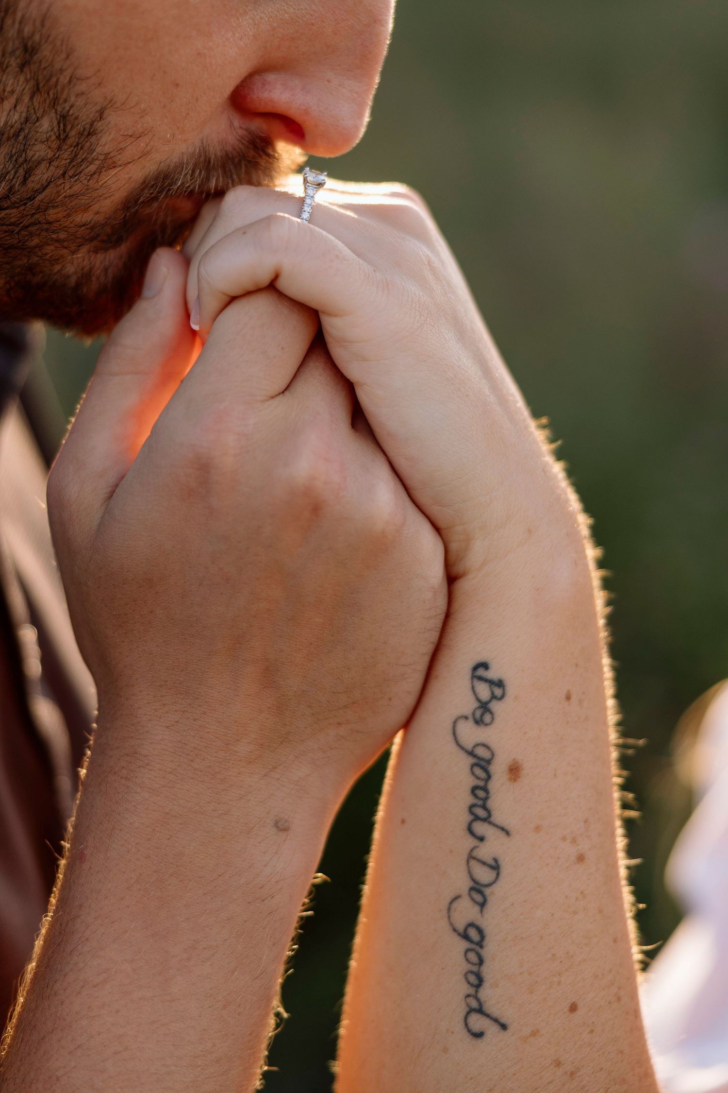Detailed shot of hands with cursive tattoo in golden afternoon light during Rochester, NY engagement photos at Lake Ontario.