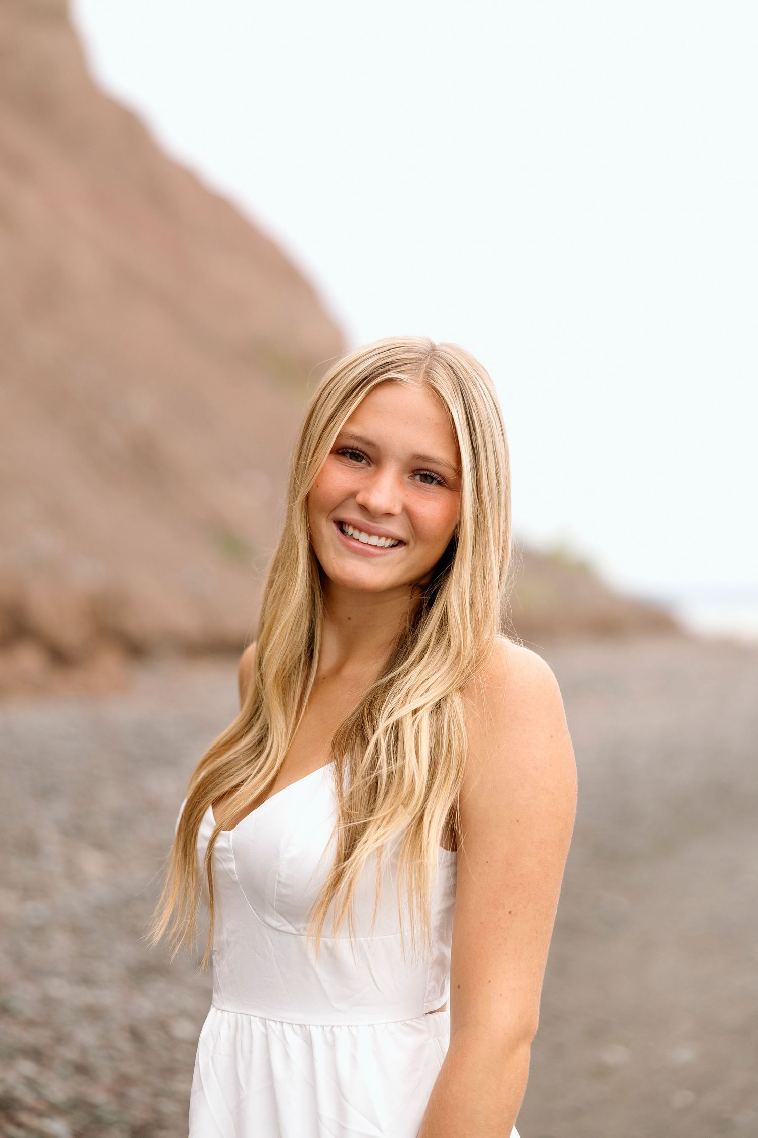 A summer portrait session in a white dress against a bright outdoor background at Chimney Bluffs State park for Rochester NY senior portaits