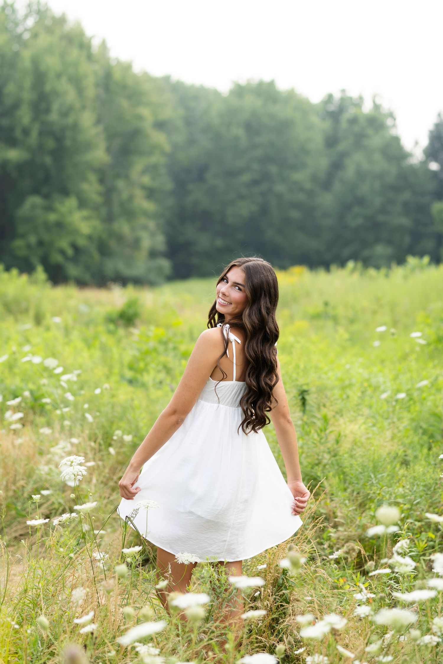 Whimsical high school senior photoshoot in wildflower meadow with flowing white dress at Tinker Nature Center, Rochester, NY.