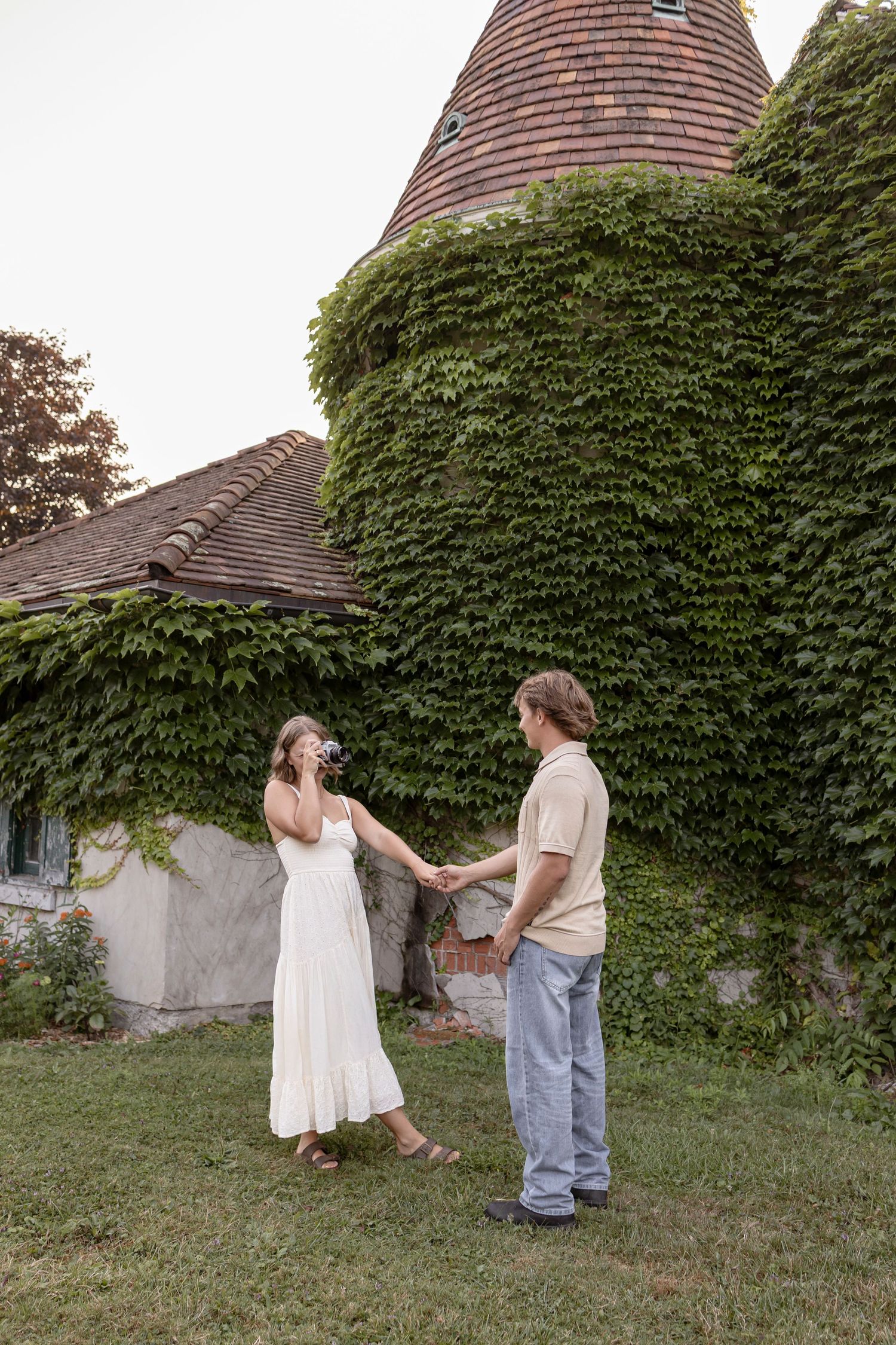 A couple taking photos and dancing together in front of an ivy-covered building at Knox Farm State Park, Buffalo, for couples photos.