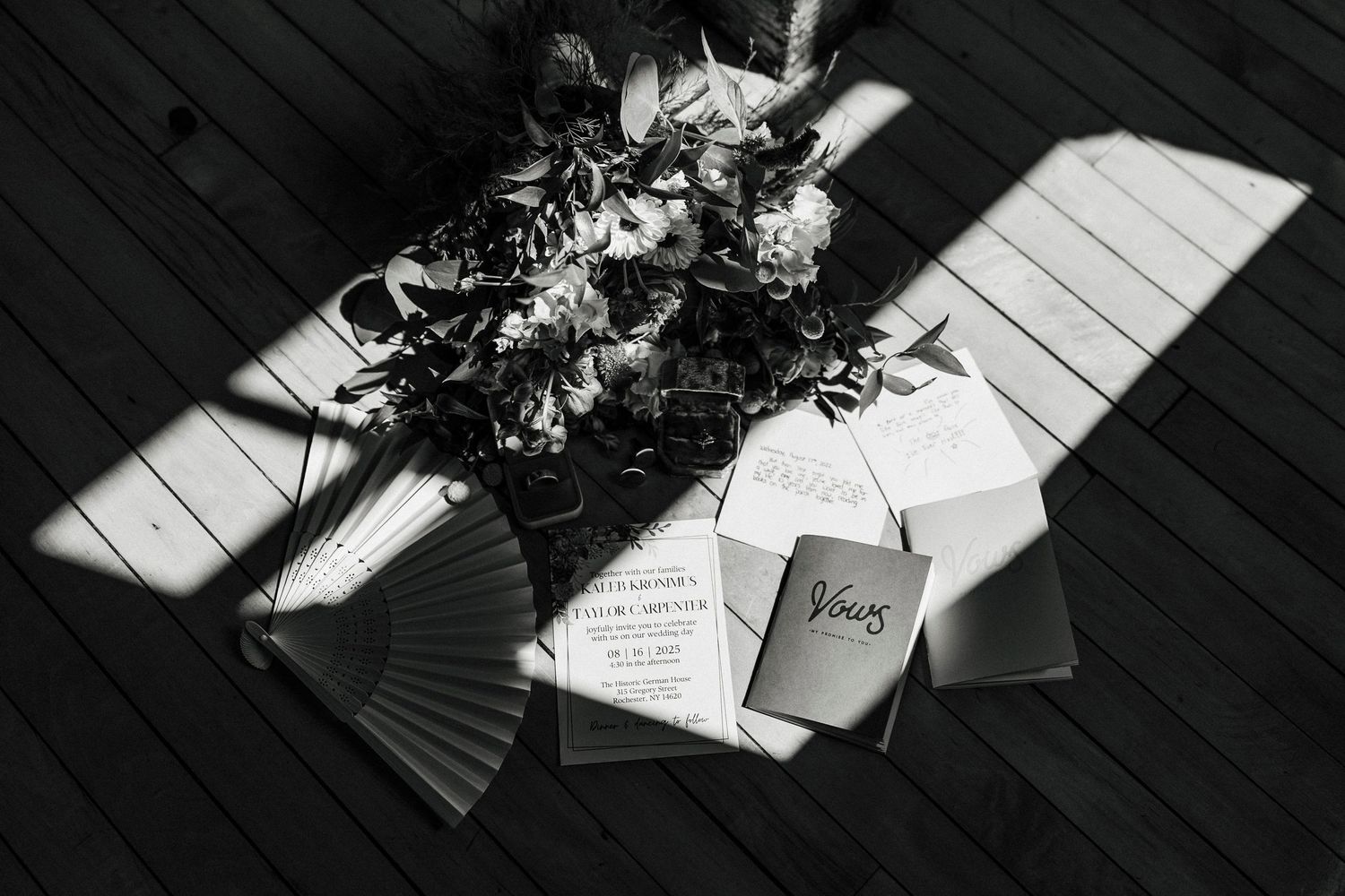 Black and white detail photo of wedding stationery in dramatic window lighting.