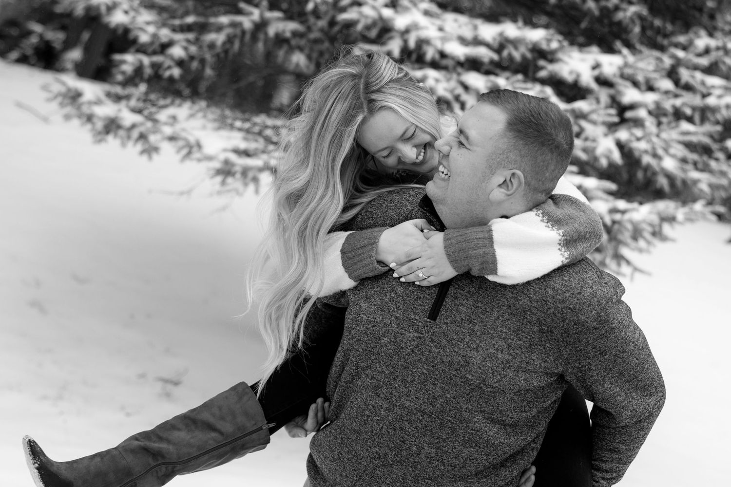 Black and white portrait of couple sharing joyful moment in snowy setting at Highland Park for Rochester NY engagement photos.