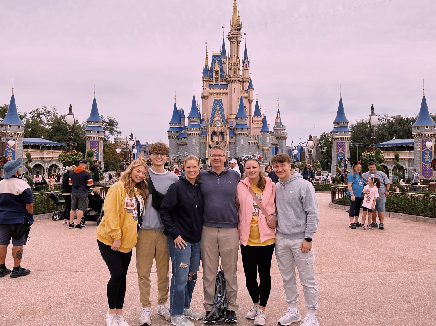 Family of six posing in front of Cinderella Castle at Walt Disney World Magic Kingdom park.