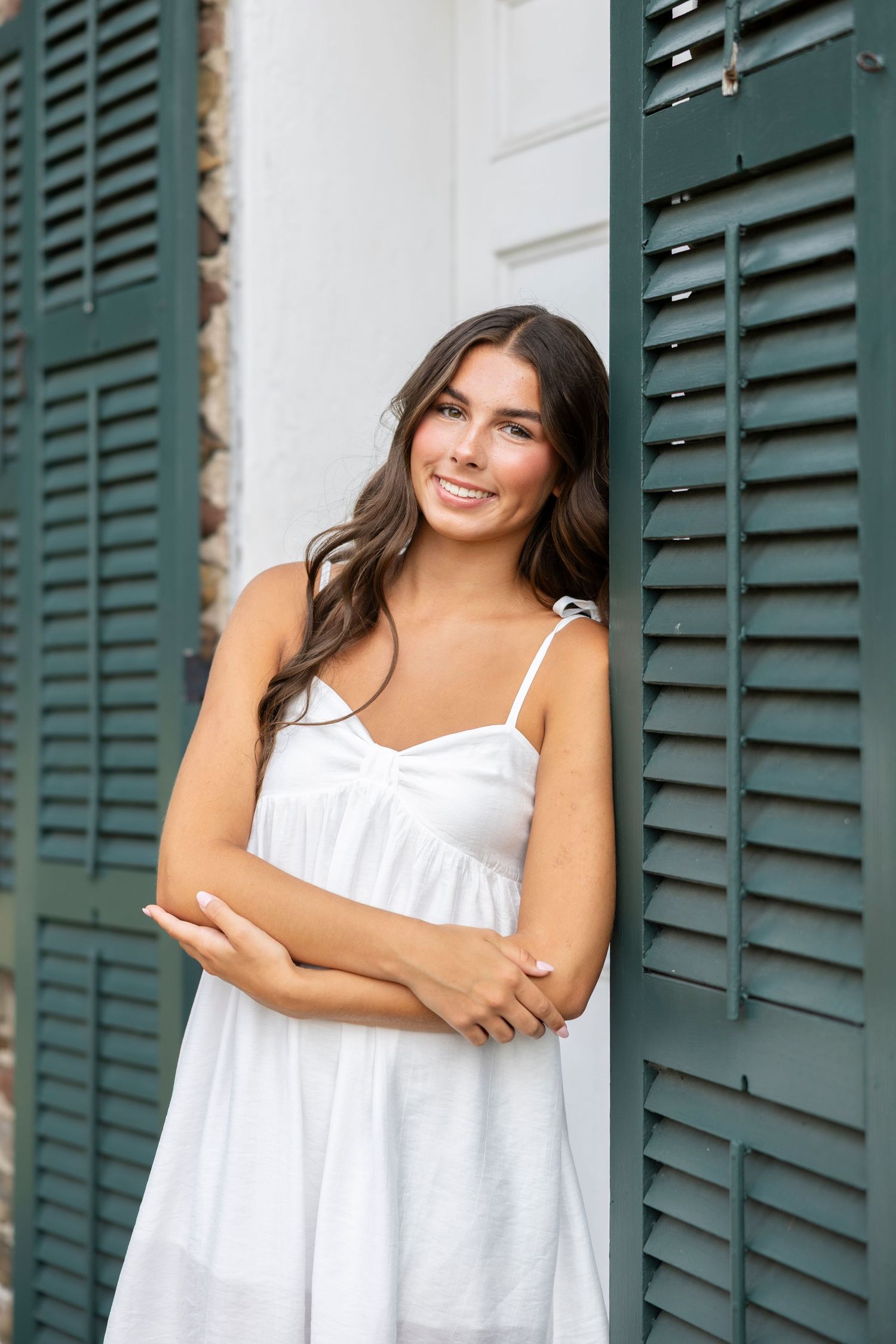 Portrait series against white wall with green shutters in summer attire at Tinker Nature Center for Rochester NY senior portaits.