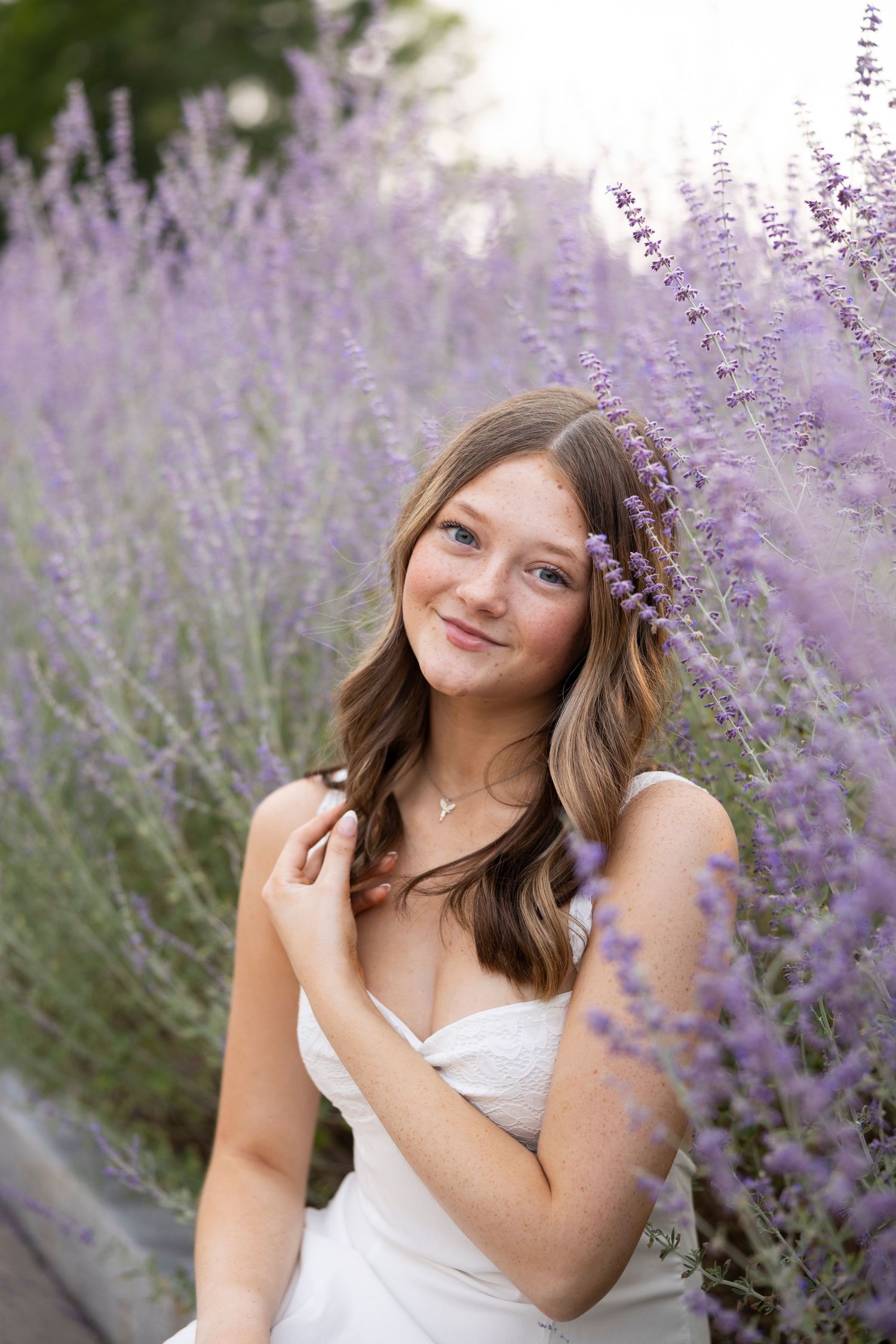 Summer portrait session in white dress among blooming lavender flowers during senior portaits at the George Eastman House, Rochester, NY.