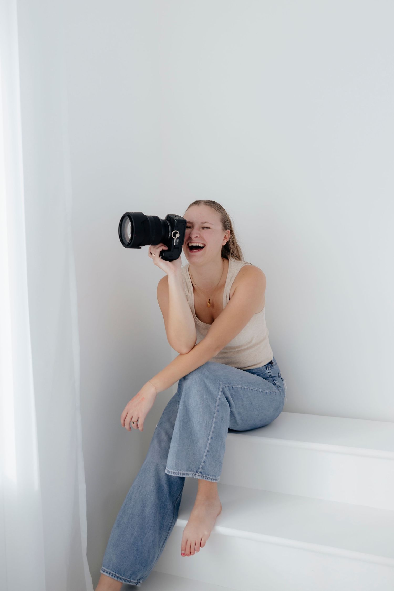 Creative self-portrait series of a photographer in casual wear using a camera in a white studio setting.