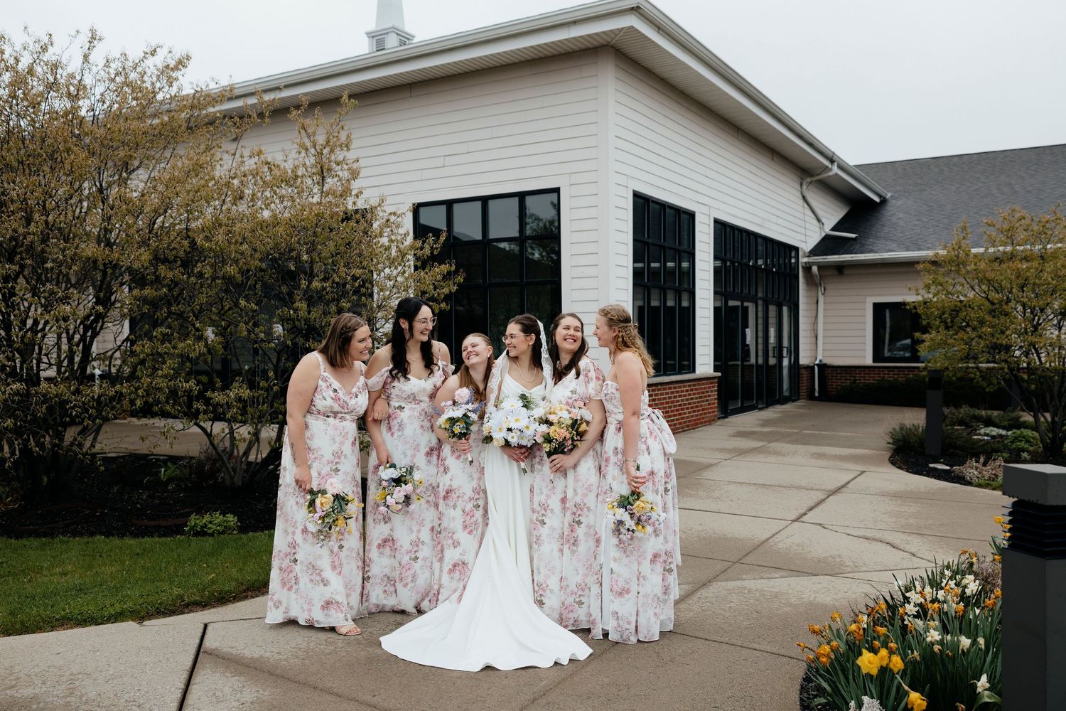 Bridal party in blush pink dresses poses outside church on wedding day in Batavia NY.