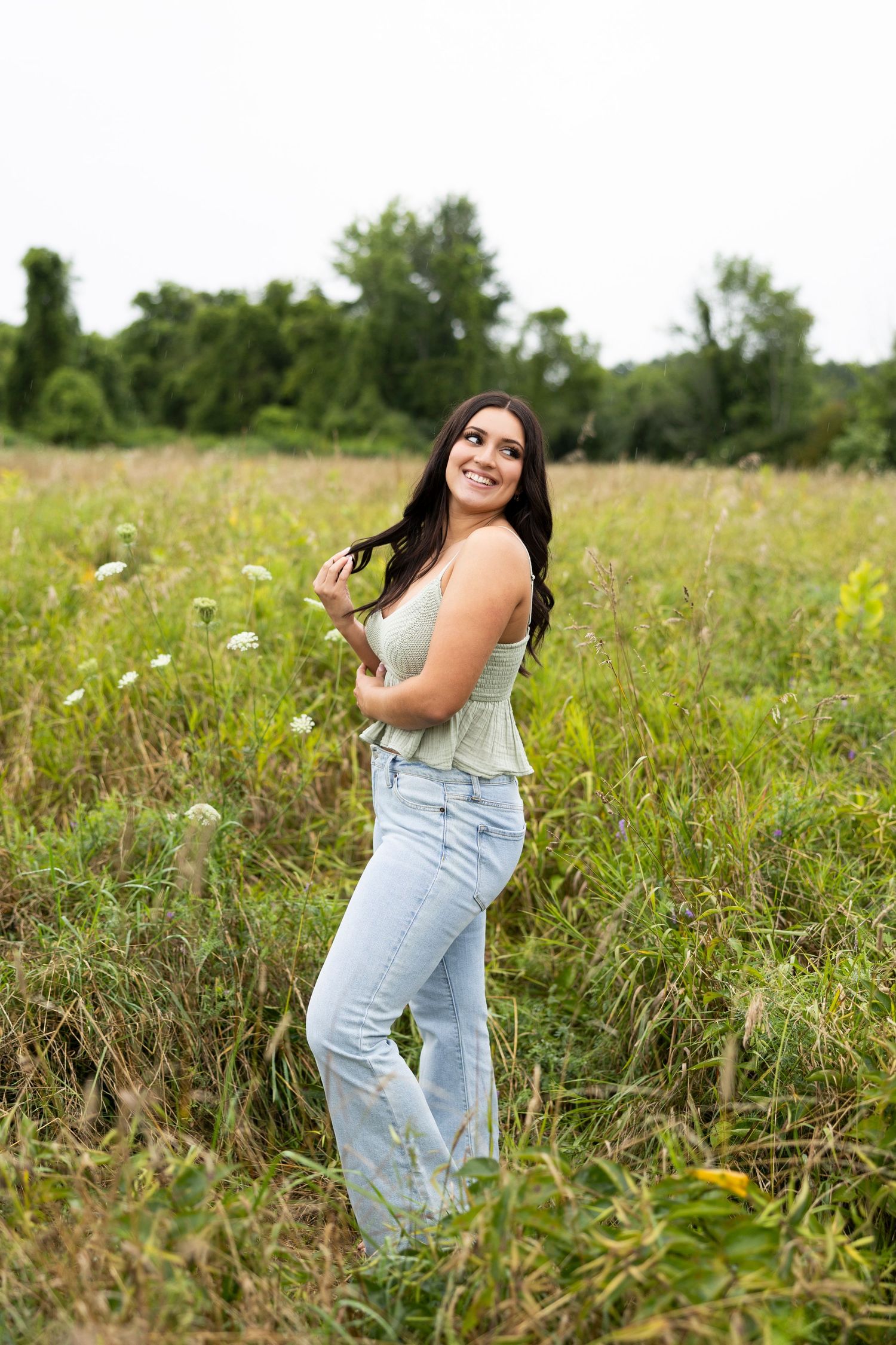 Candid portrait session in overalls against a natural wildflower field backdrop in Spencerport NY for Rochester senior photos.