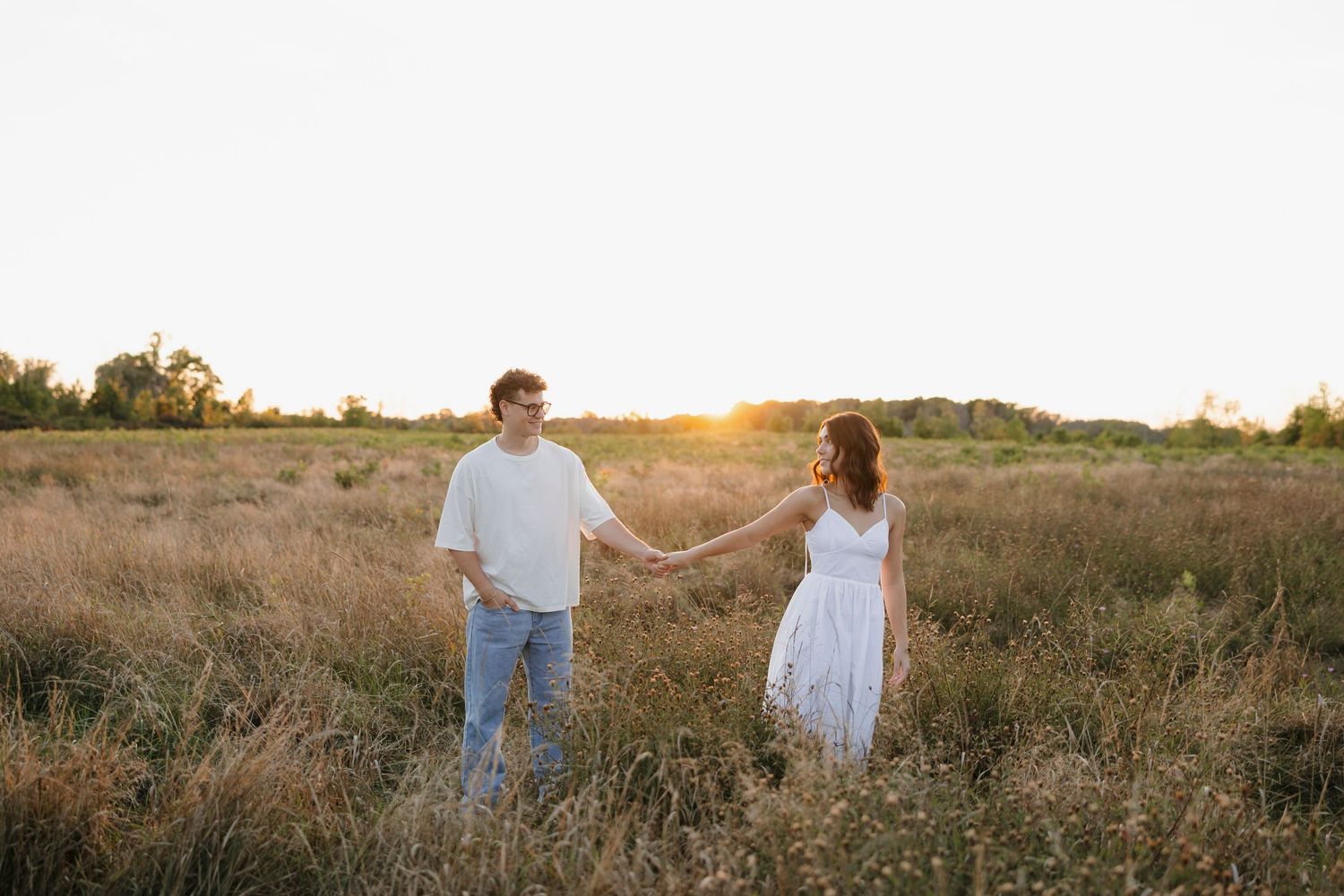 Sunset engagement photos in a golden field with warm light and natural landscape in Hilton, NY engagement photos.