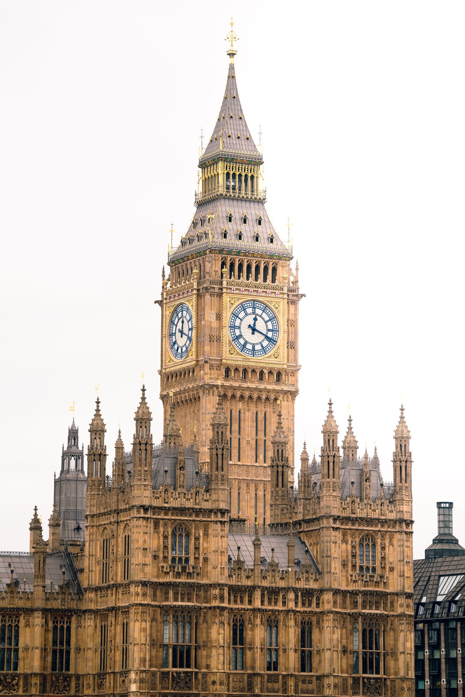 Big Ben clock tower and Houses of Parliament in London against white sky.
