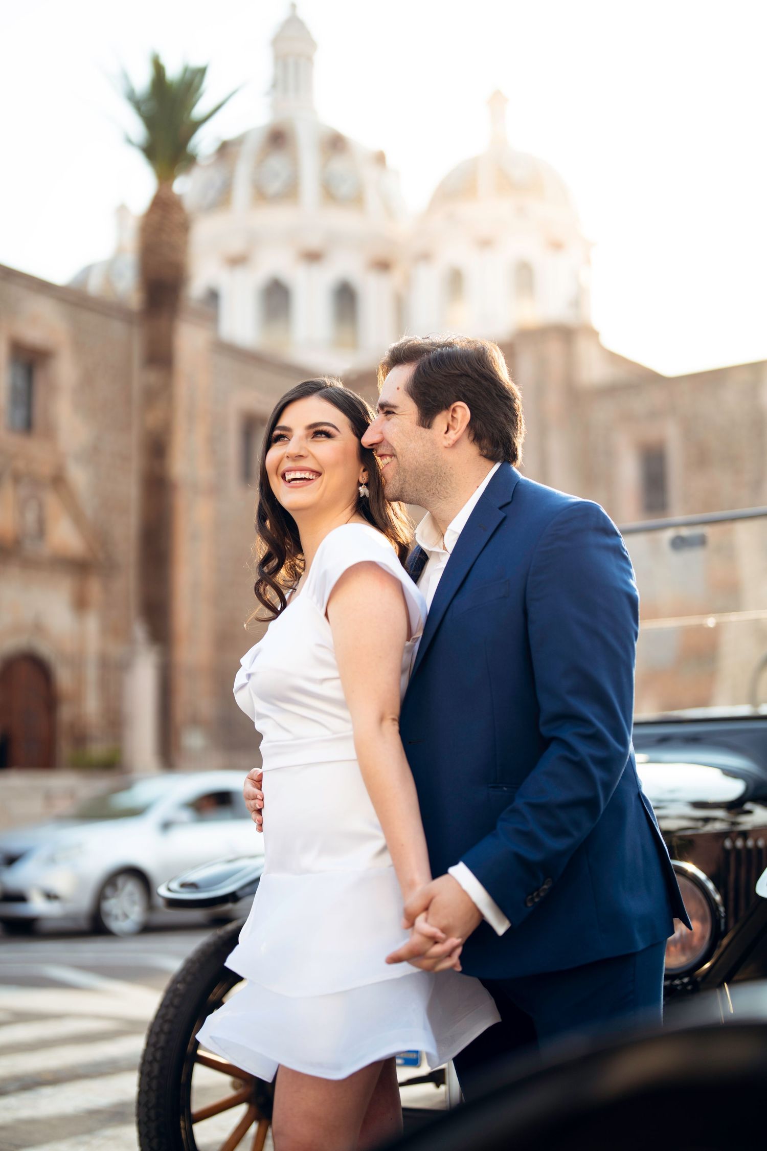 A romantic moment captured outside a historic Spanish-style building.
