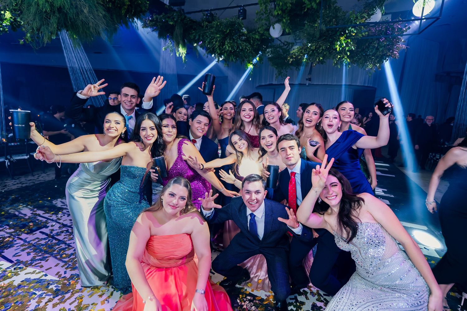 Festive party celebration with large crowd dancing under dramatic blue lighting.