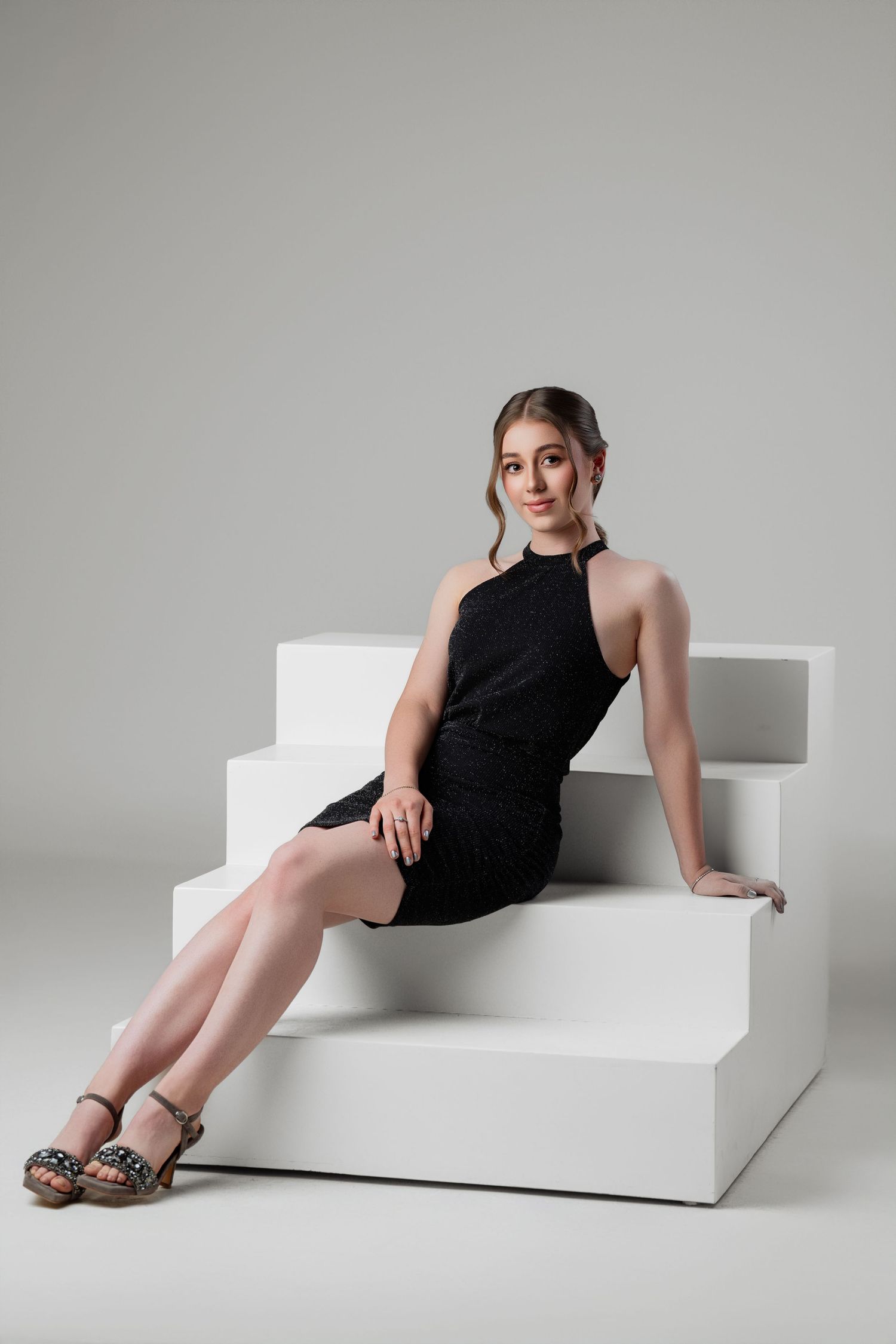 Minimalist fashion photoshoot on white geometric platform with black outfit and leopard print shoes.