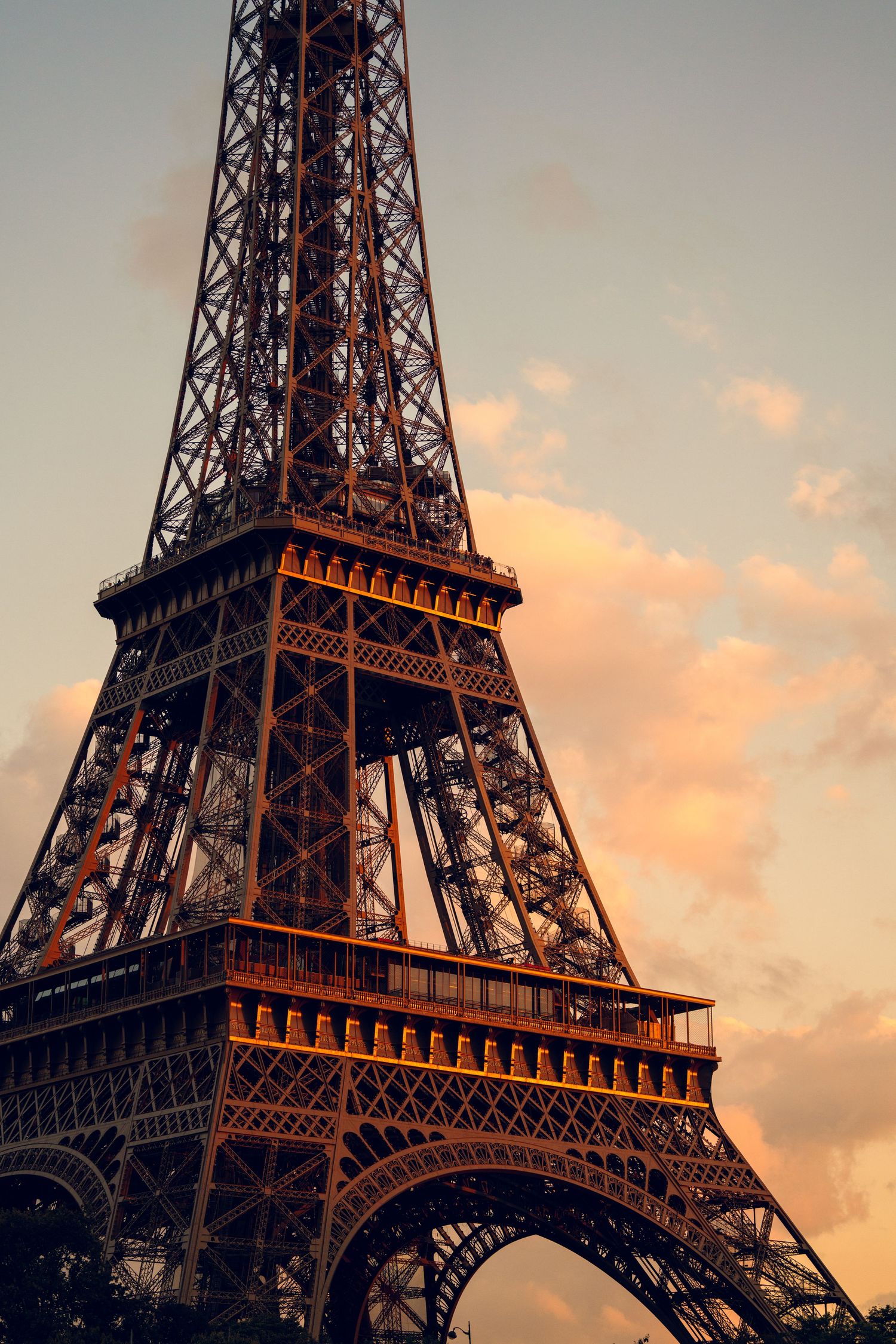 Eiffel Tower photographed at sunset with warm golden light illuminating its iconic iron structure.