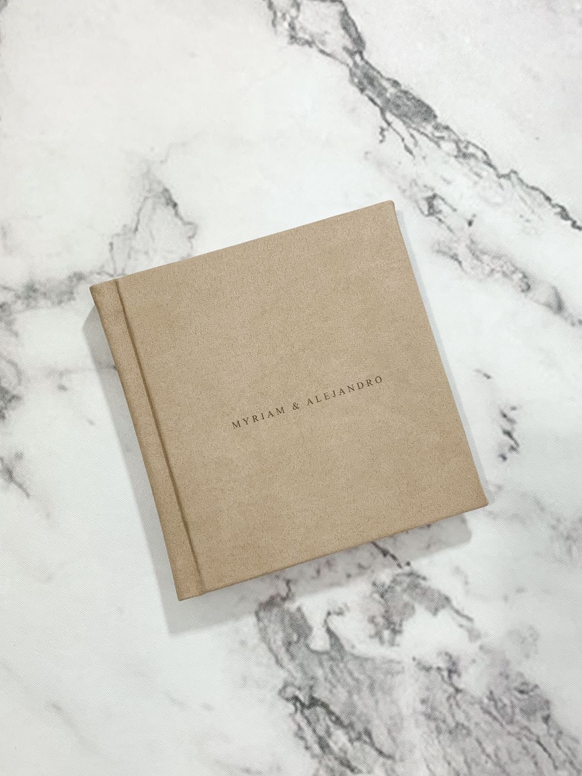 Minimalist kraft paper wedding invitation on white marble background.