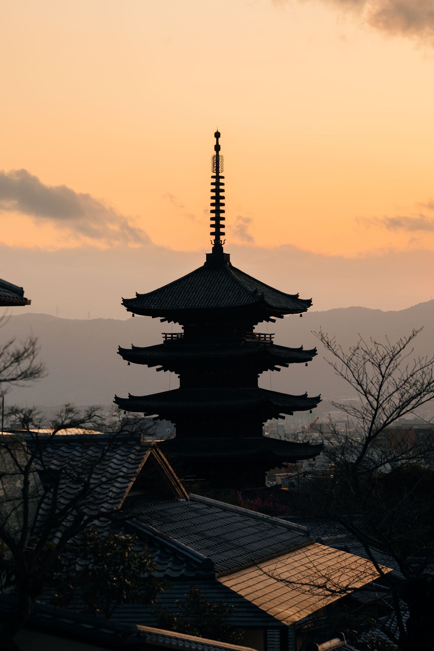 Traditional Japanese pagoda silhouettes against an orange sunset sky.