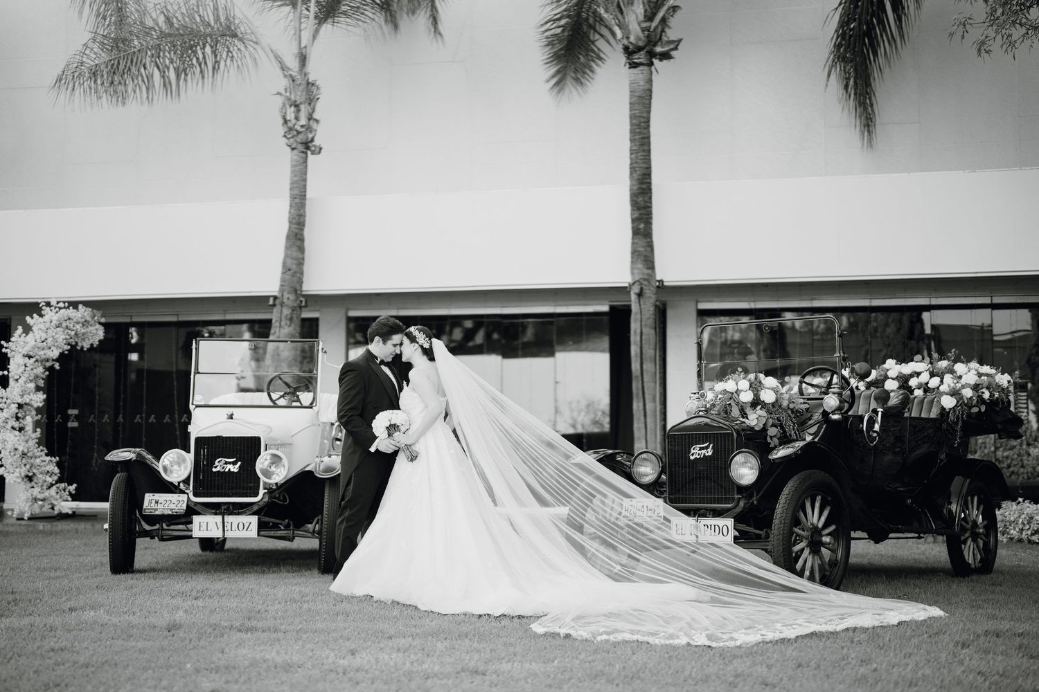 Black and white wedding photos with palm trees and long train of dress visible.