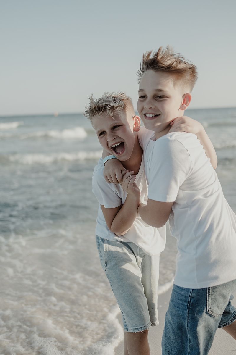 Playful moment of two brothers laughing together during beach family photoshoot in Playa del Carmen.