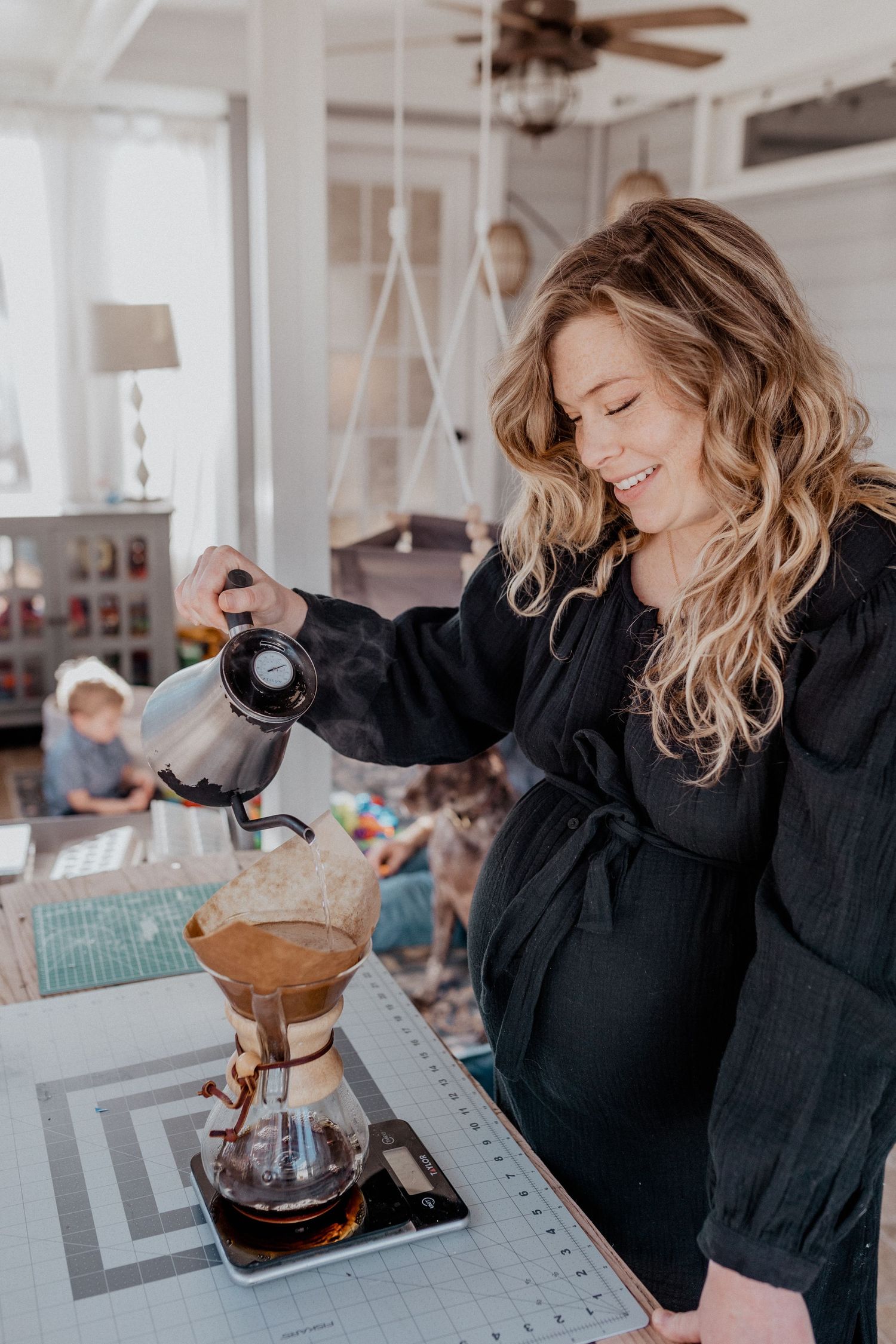 mom making coffee in sunroom of home in chesapeake, virginia maternity photos