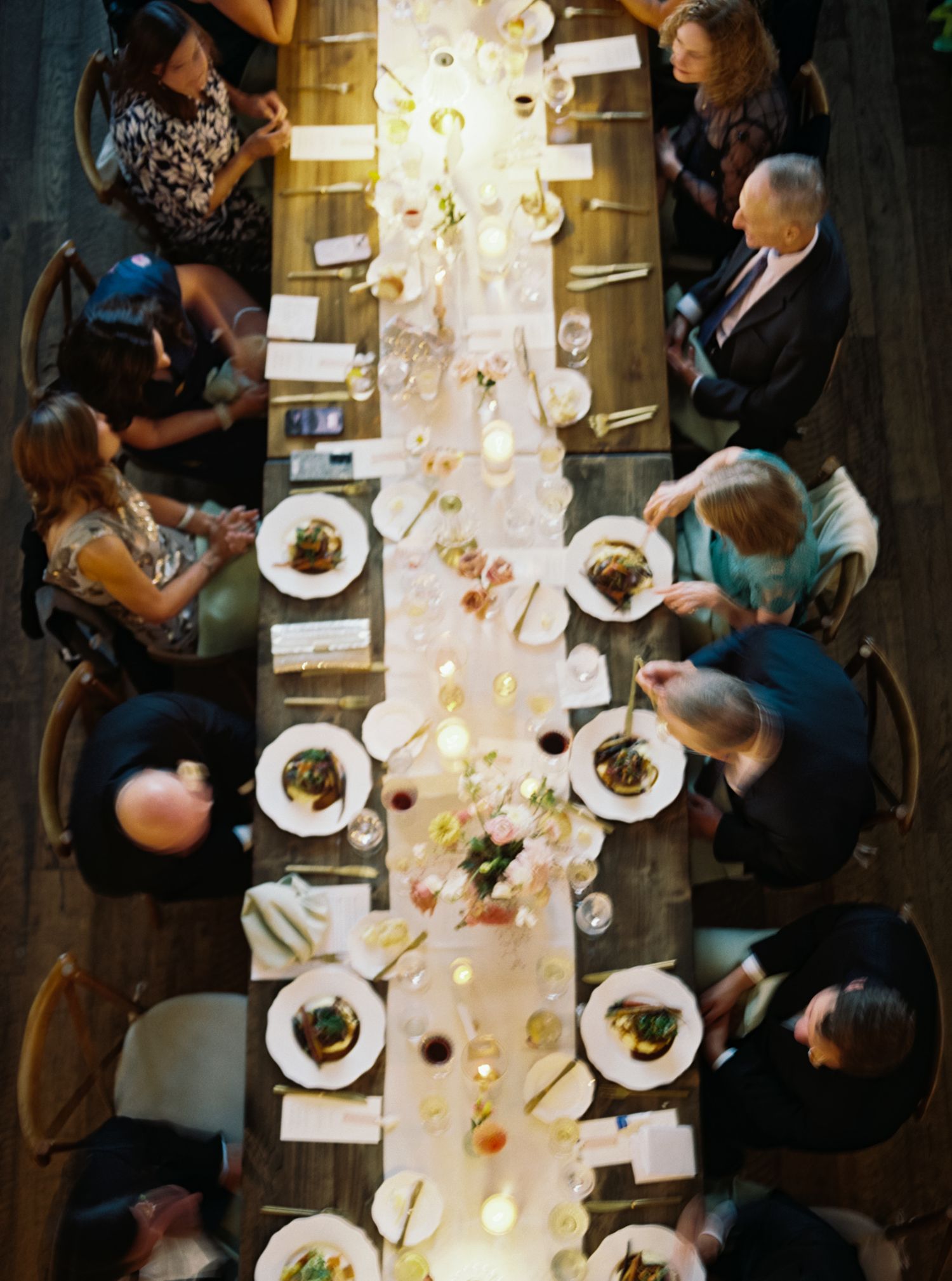 Overhead view of an elegant wedding reception dinner table with glowing lights and place settings.