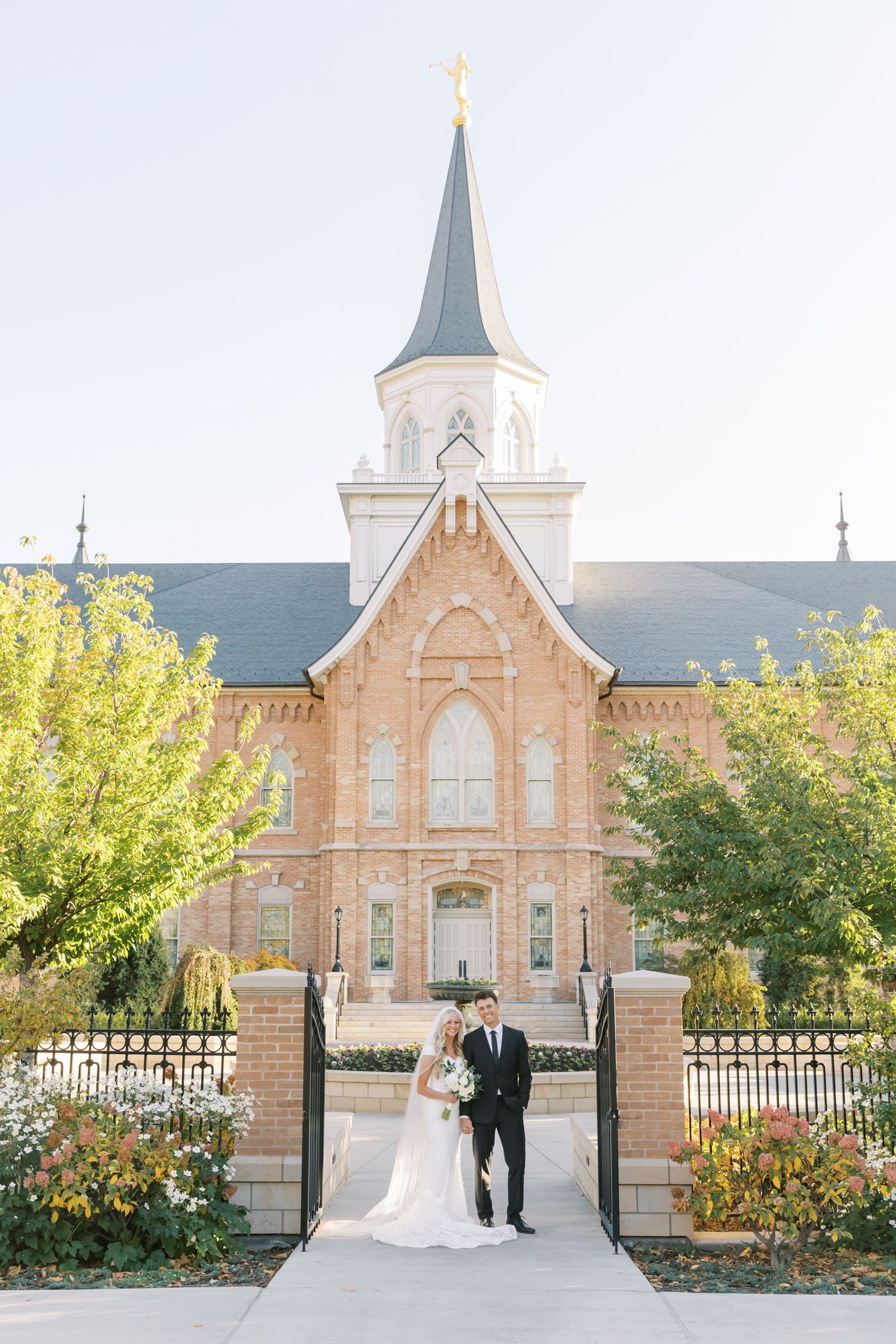 Elegant wedding portrait in front of historic church with white steeple.