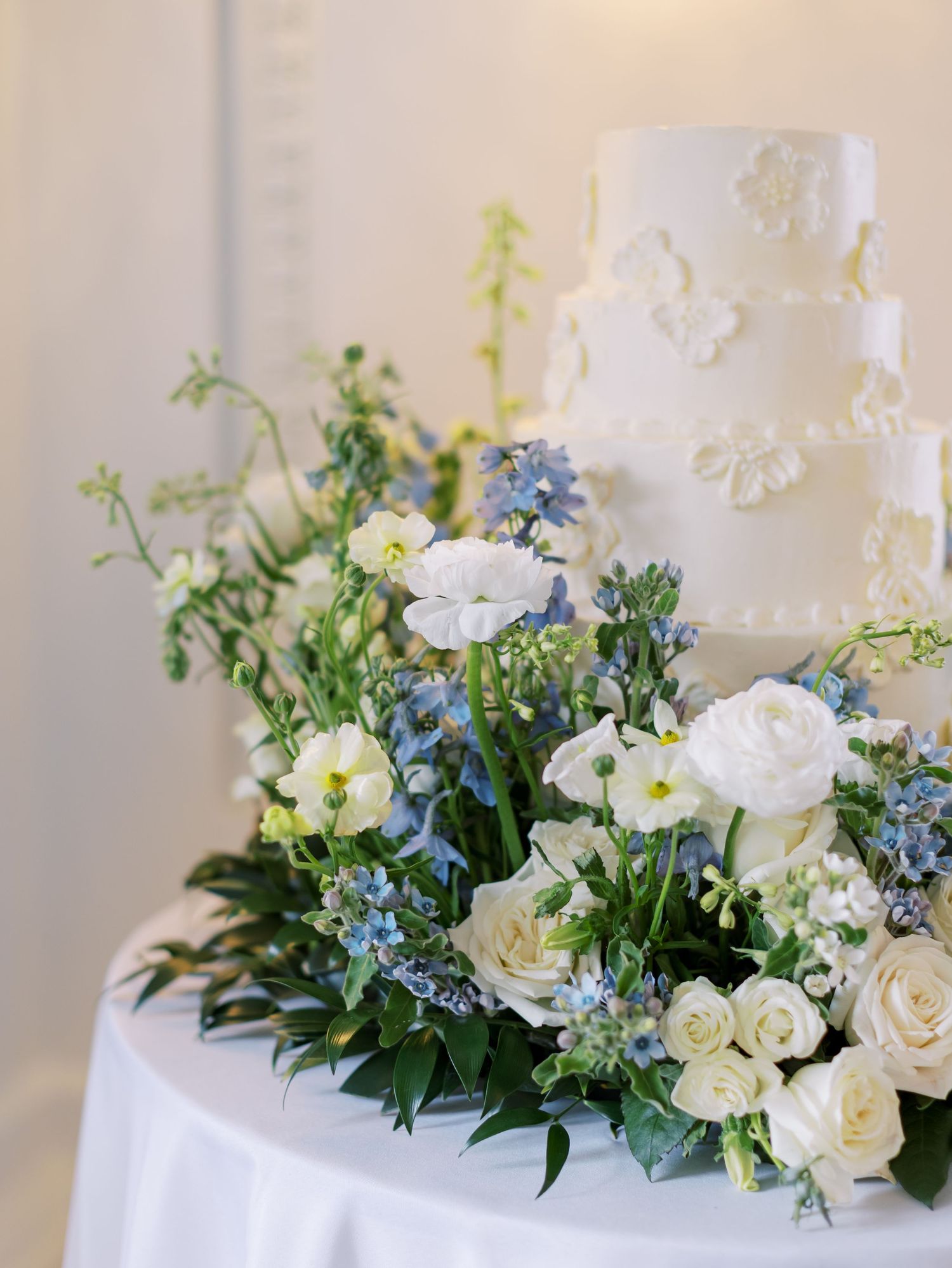 White and blue floral wedding cake decorations featuring roses, hydrangeas, and delicate greenery on a classic tiered design.