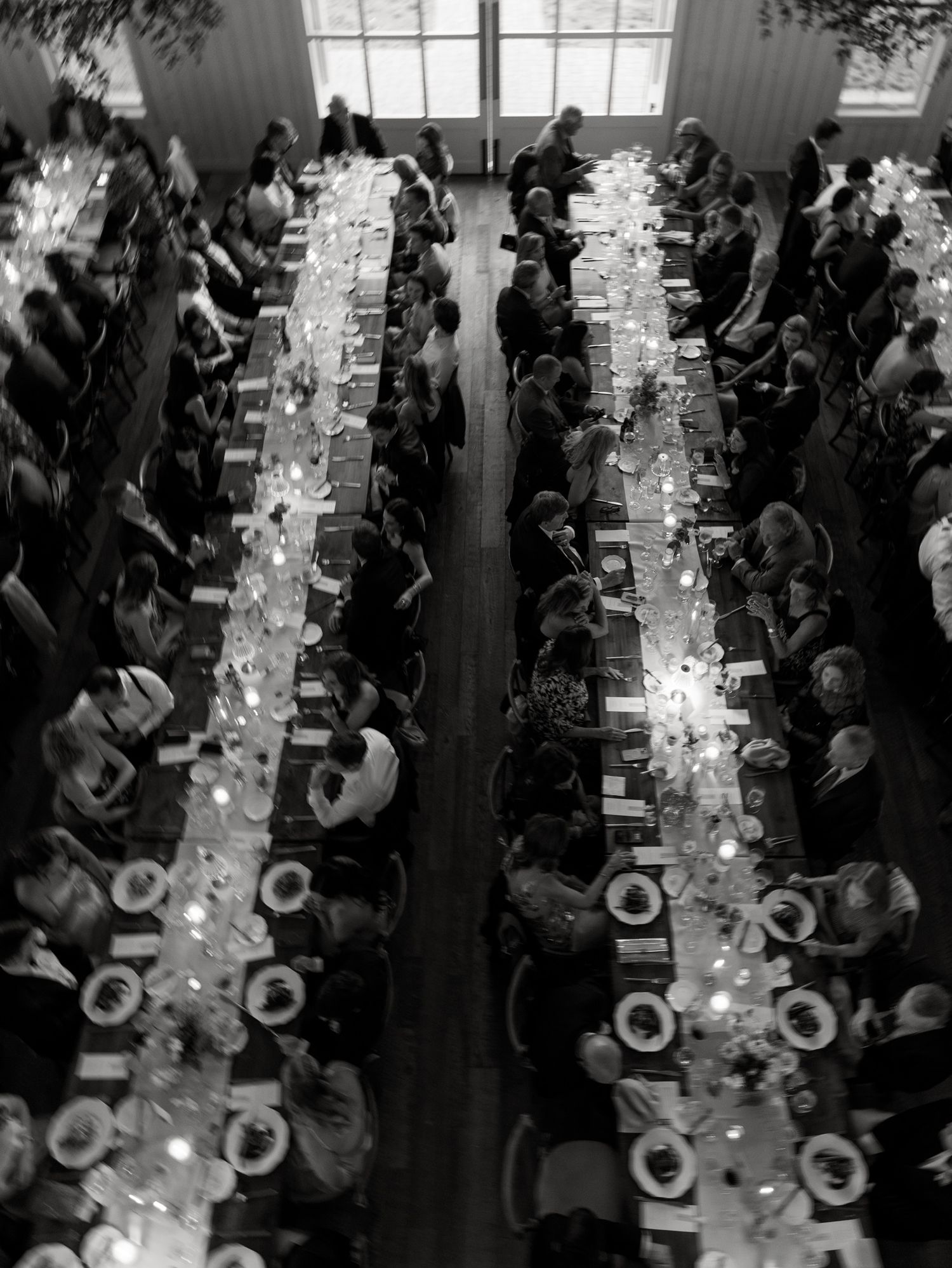 Aerial view of a formal dinner event with long tables arranged in rows where guests are seated in a grand hall.