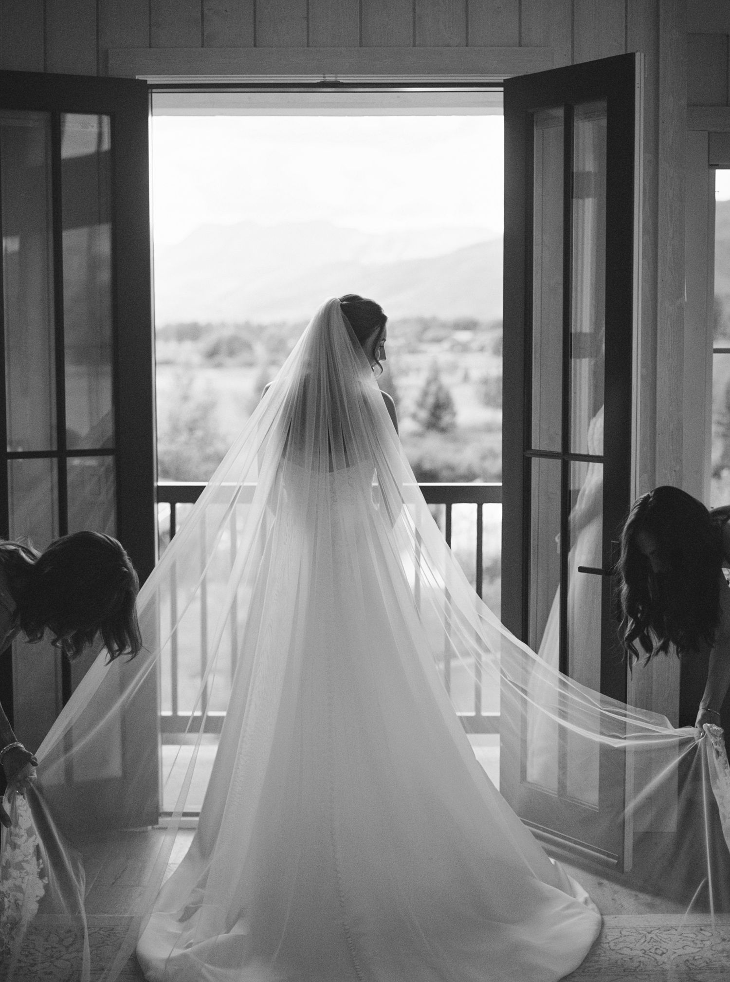Black and white photo series showing a bride in a flowing veil silhouetted against large windows.