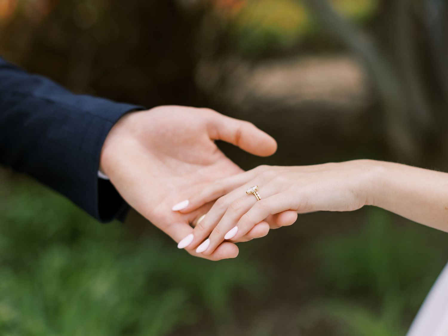 Two hands reaching out and joining together in a tender moment against a soft blurred background.