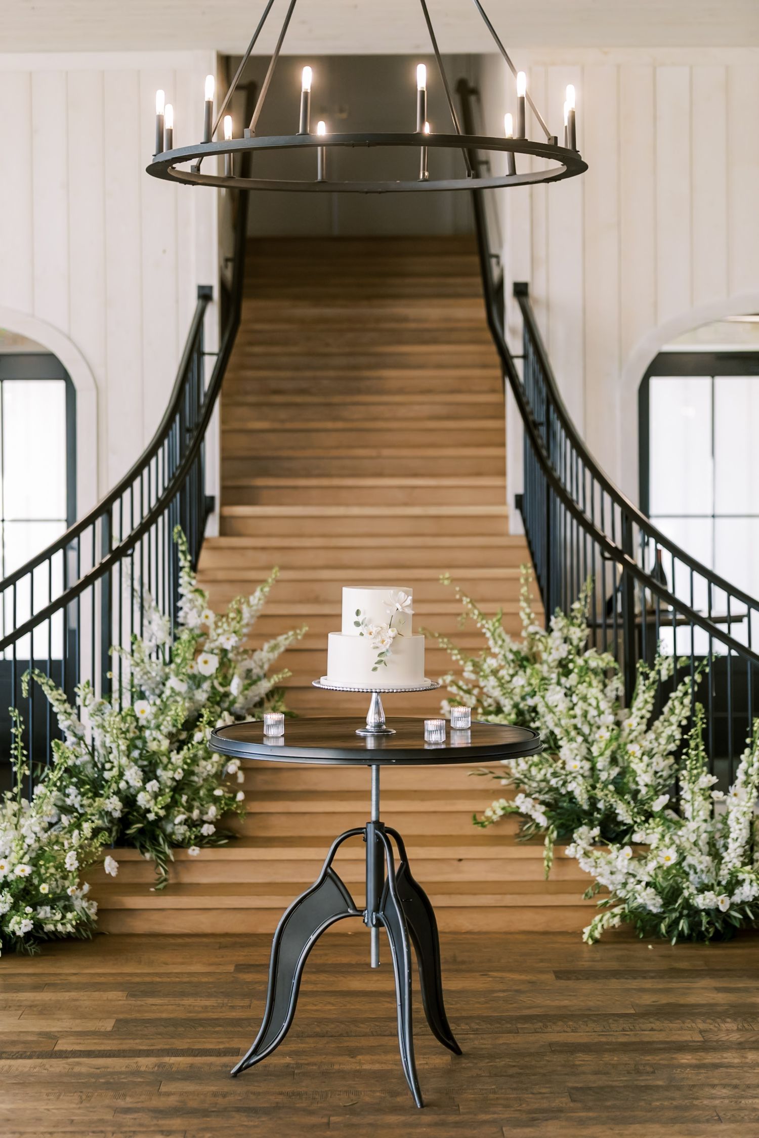 Modern wedding venue interior with wooden staircase and elegant floral arrangements.
