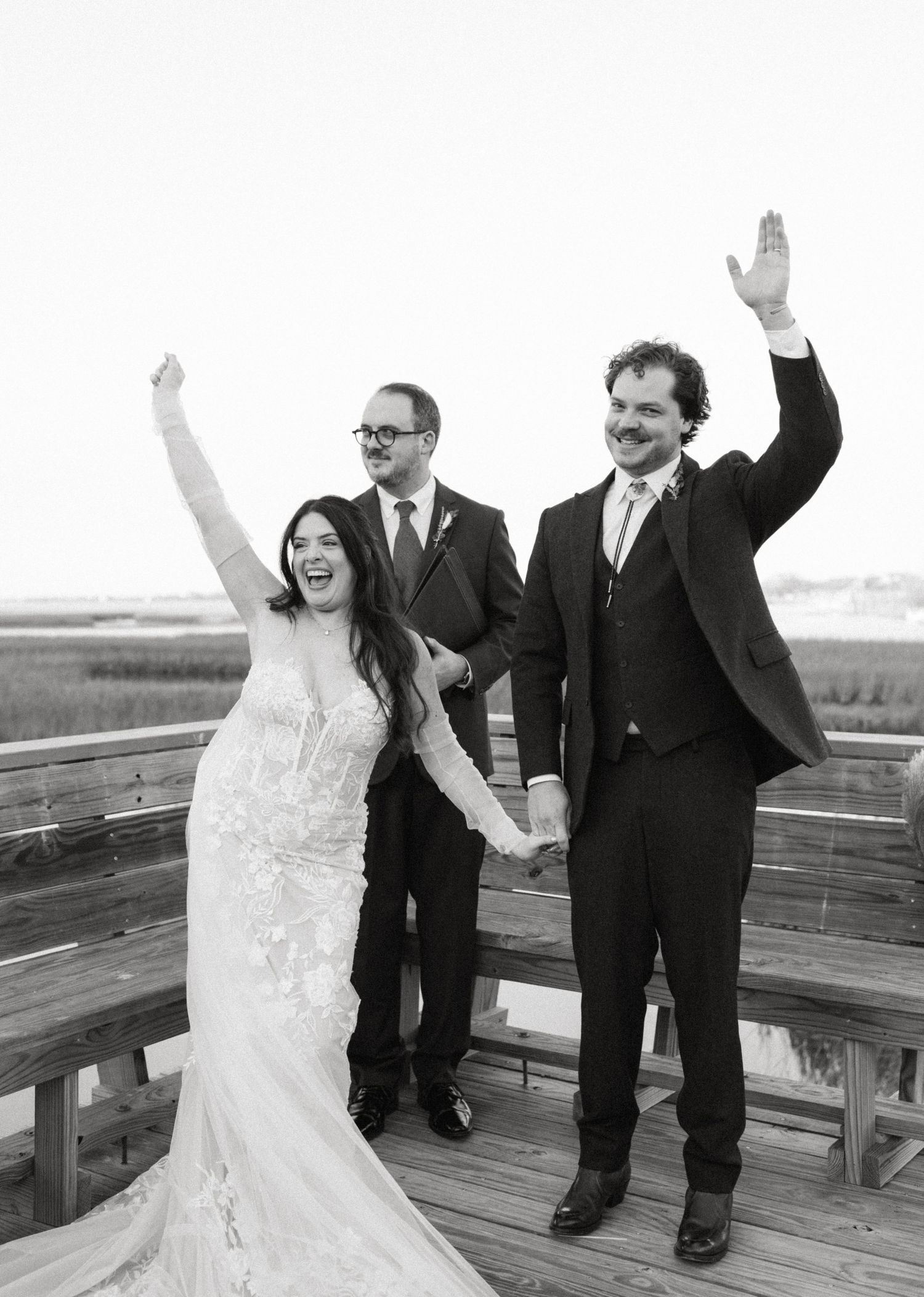 photo of a joyful bride and groom celebrating with raised arms on a wooden deck in New York City after their wedding ceremony.