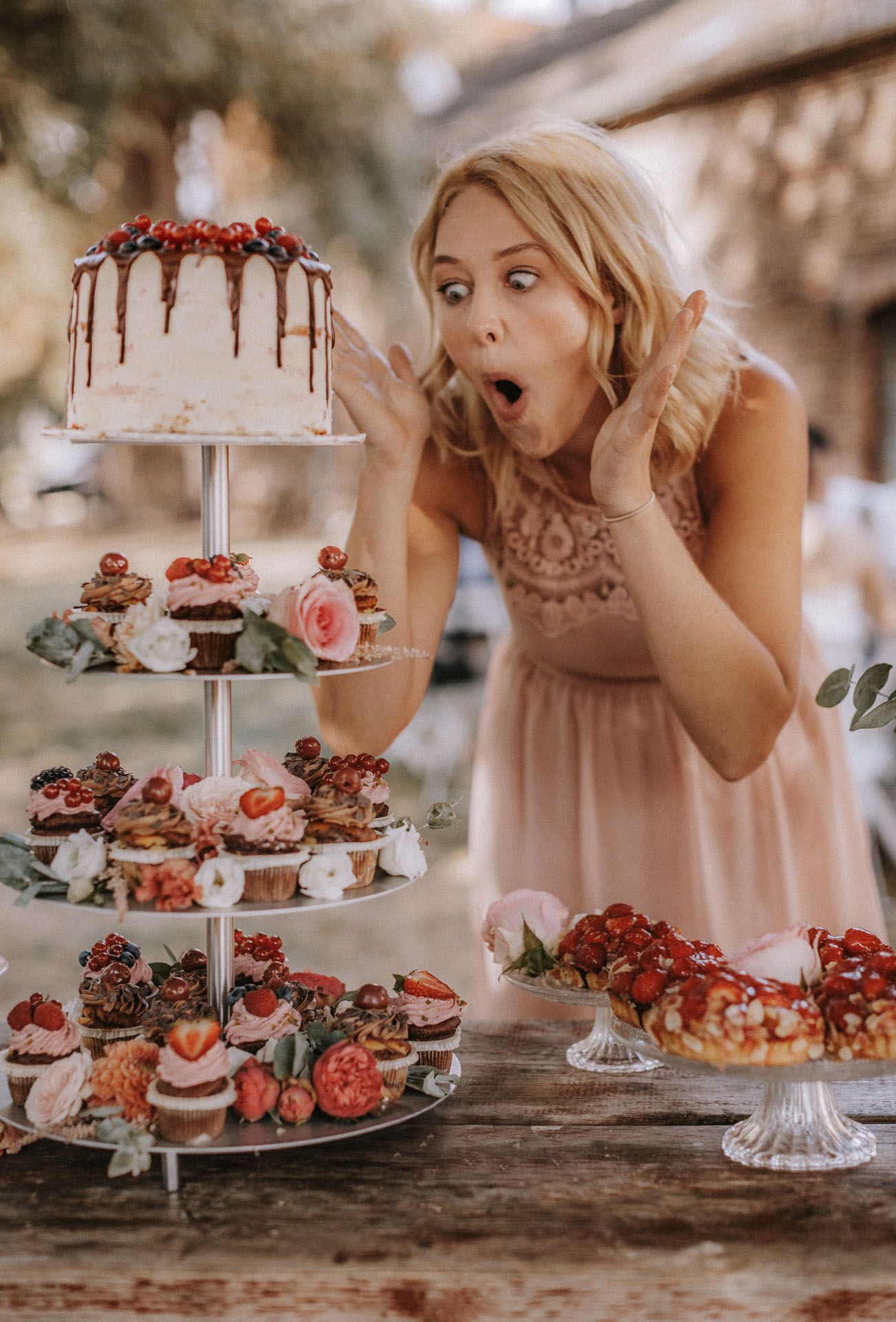 A whimsical dessert display featuring a tiered cake and cupcakes decorated with berries.