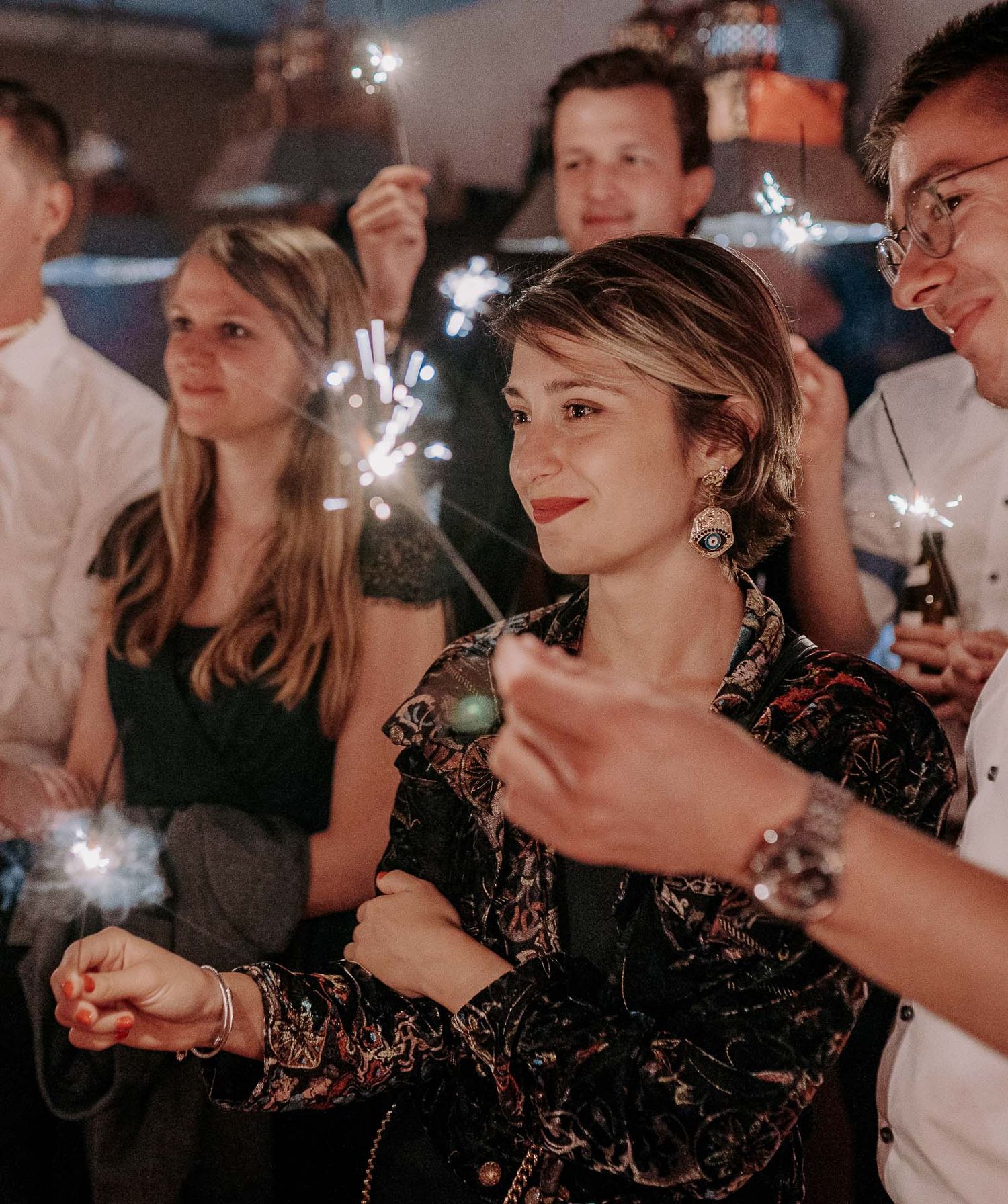 A group celebrating with sparklers at a festive nighttime gathering.