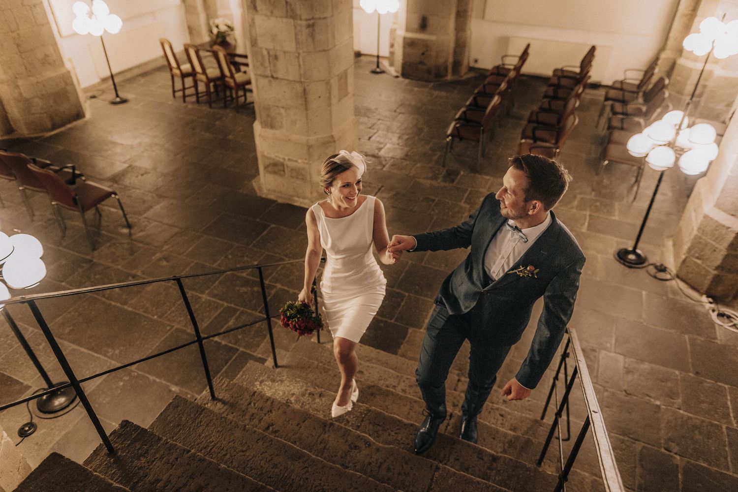 A couple descending stone stairs in an elegant venue.
