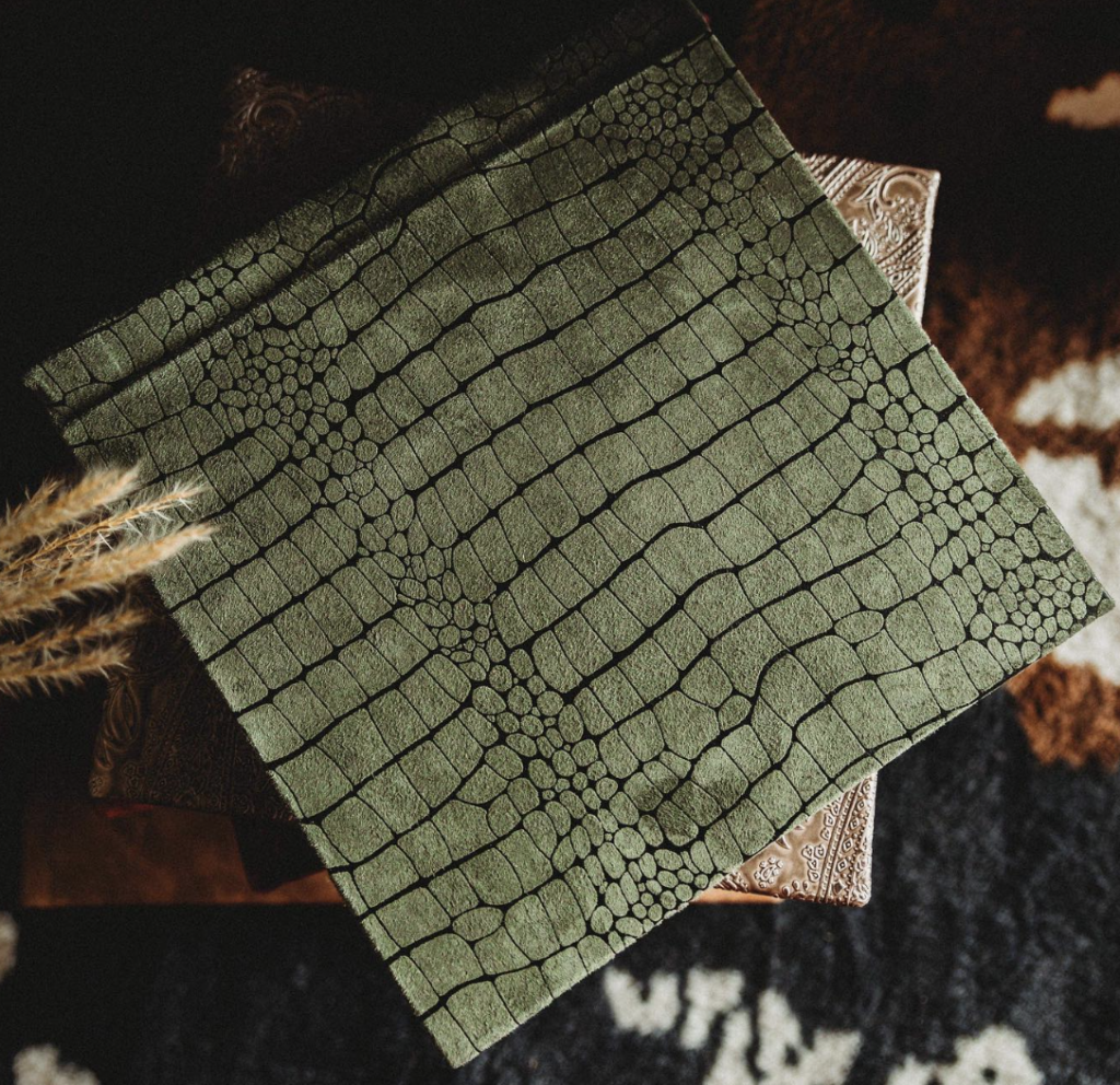 Dark and moody close-up of a luxury boudoir album with elegant linen texture and fine art prints.