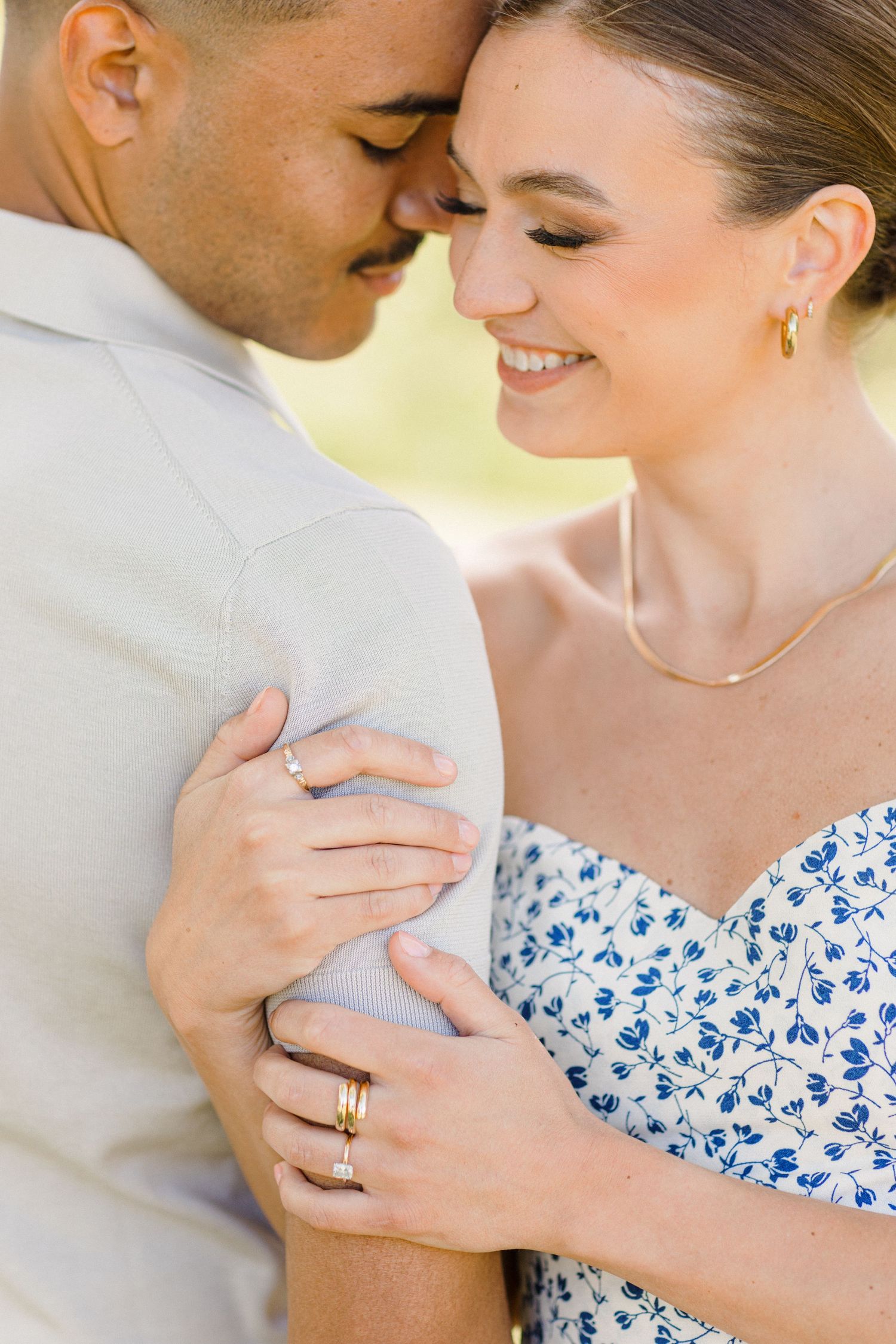An intimate romantic moment between a couple embracing, with a blue floral dress and golden jewelry visible.