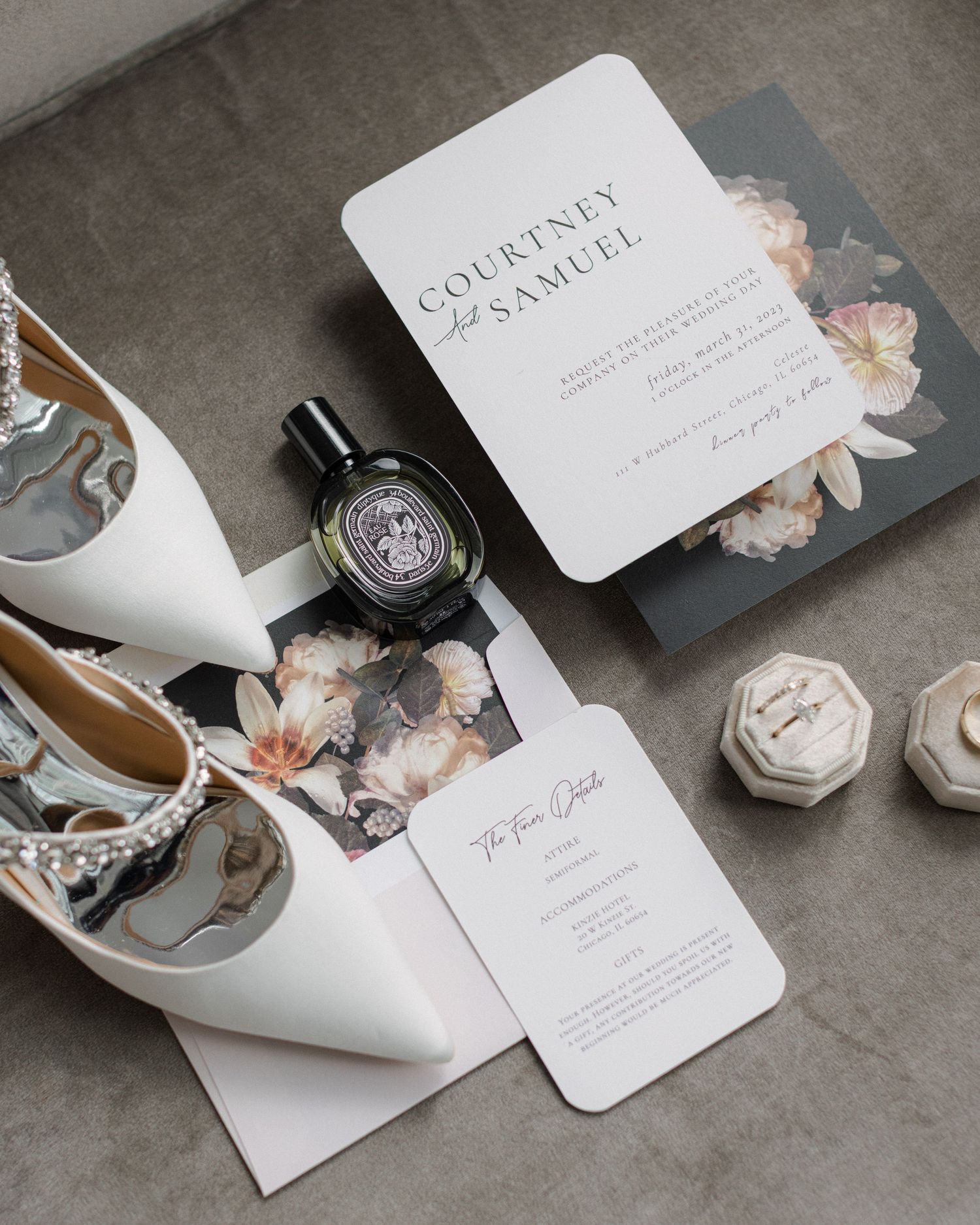Wedding details including invitation, heels, and perfume arranged on a grey surface.