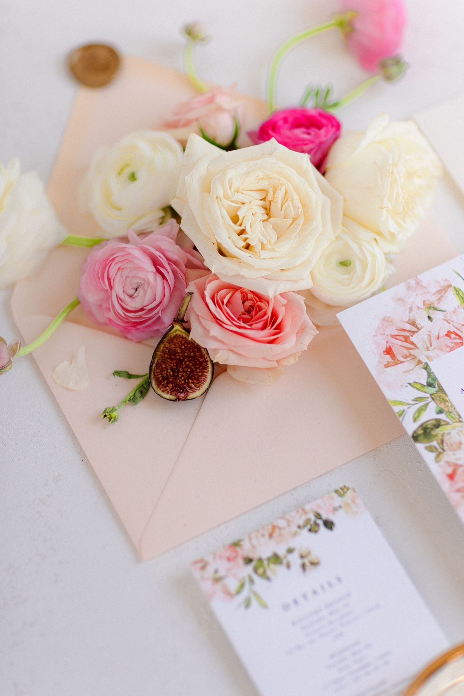 Delicate pink and white roses arranged with wedding stationery featuring floral designs.