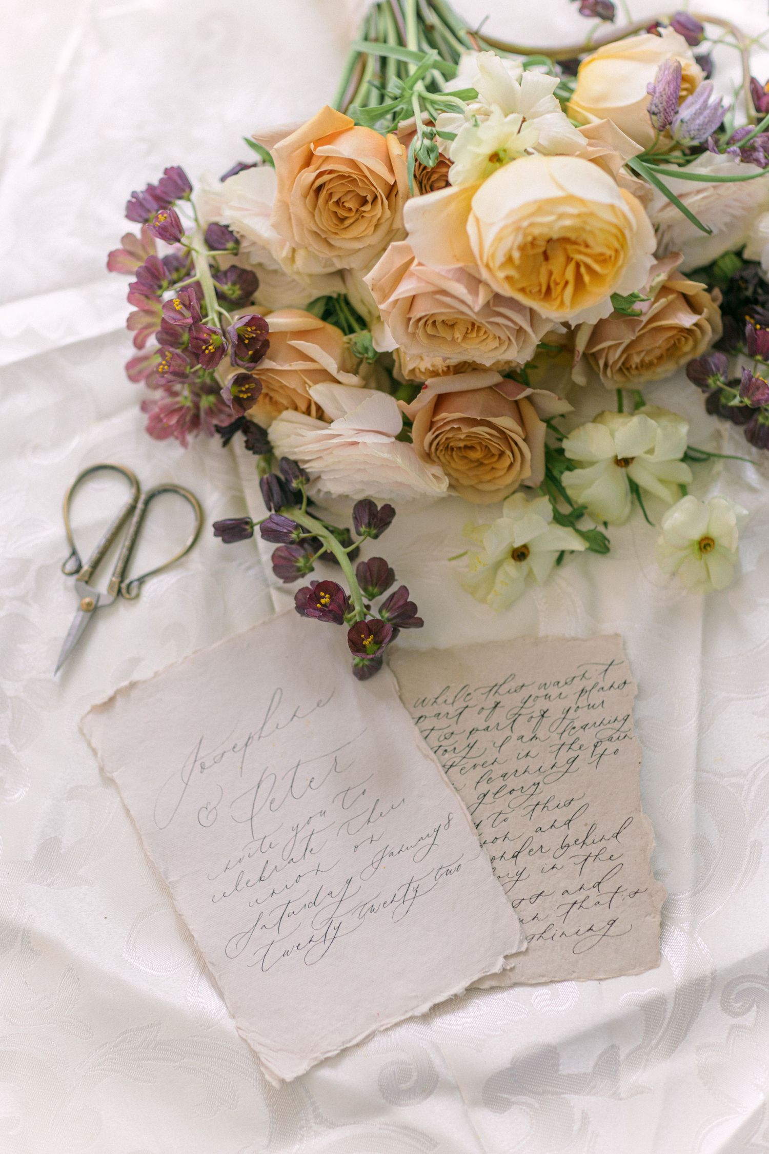 Vintage handwritten note with peach roses and purple flowers on white fabric.