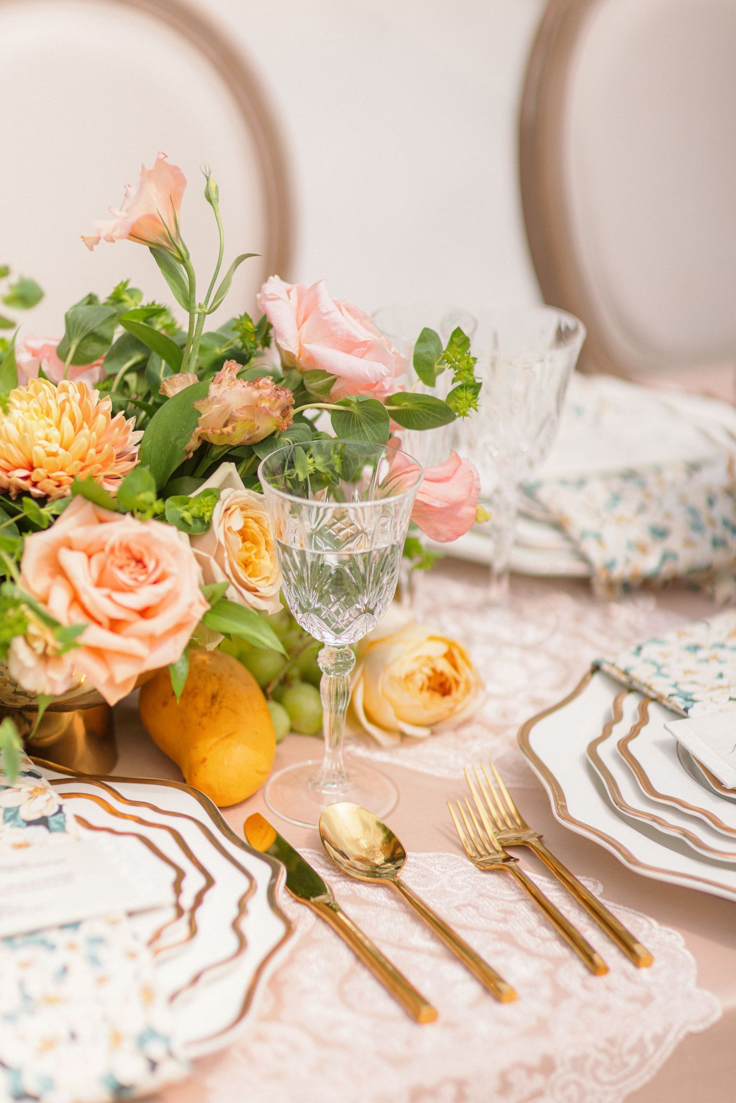 Elegant table setting with peach roses, gold flatware, and crystal glassware.