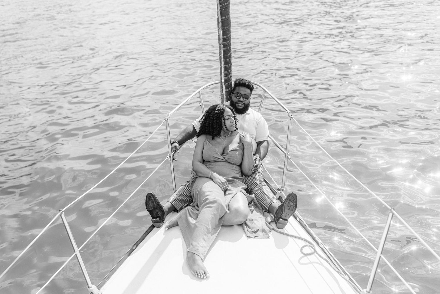 A romantic black and white photo of a couple on the bow of a boat.