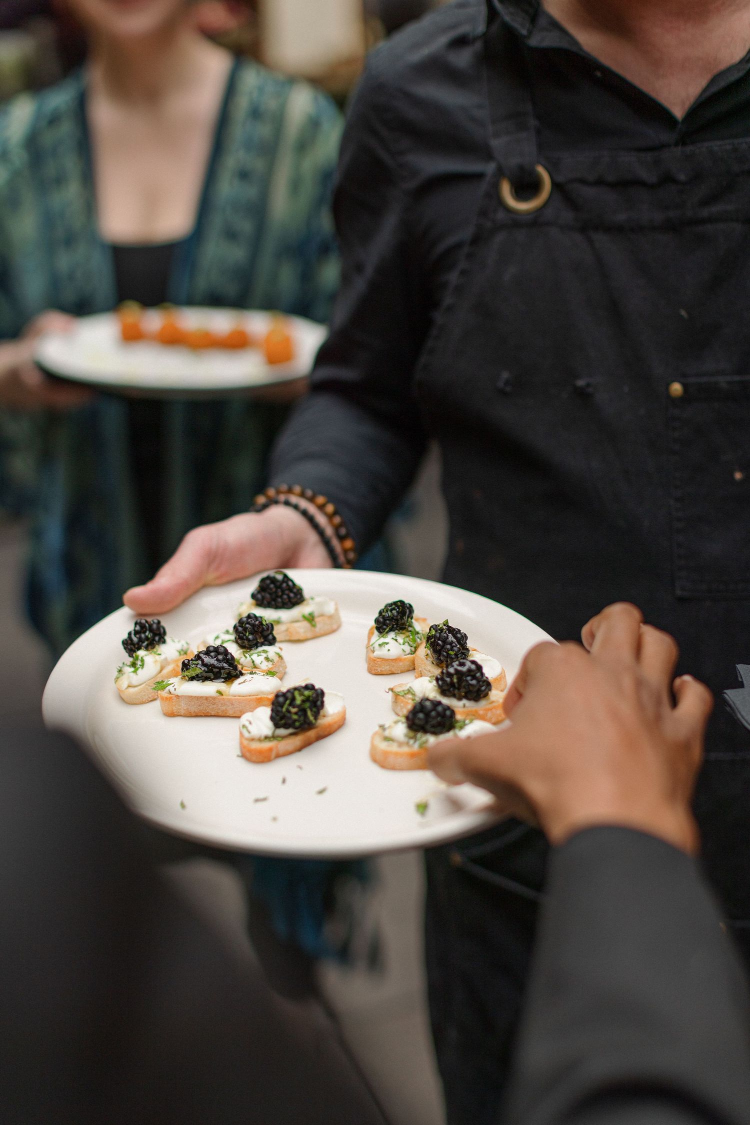 Catering staff serves elegant hors d'oeuvres topped with caviar on white plates.