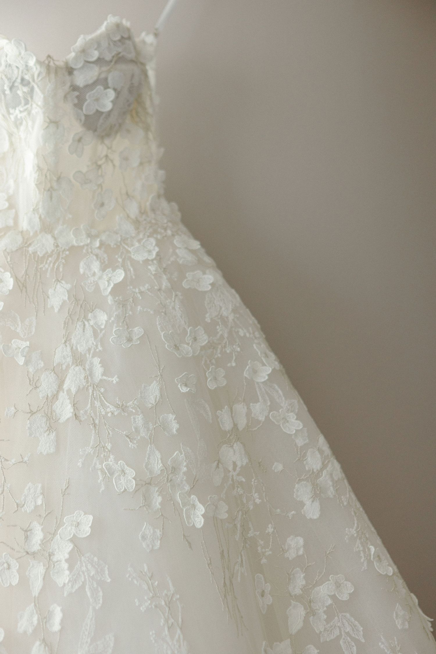 Detailed shot of delicate floral lace pattern on a white wedding gown.