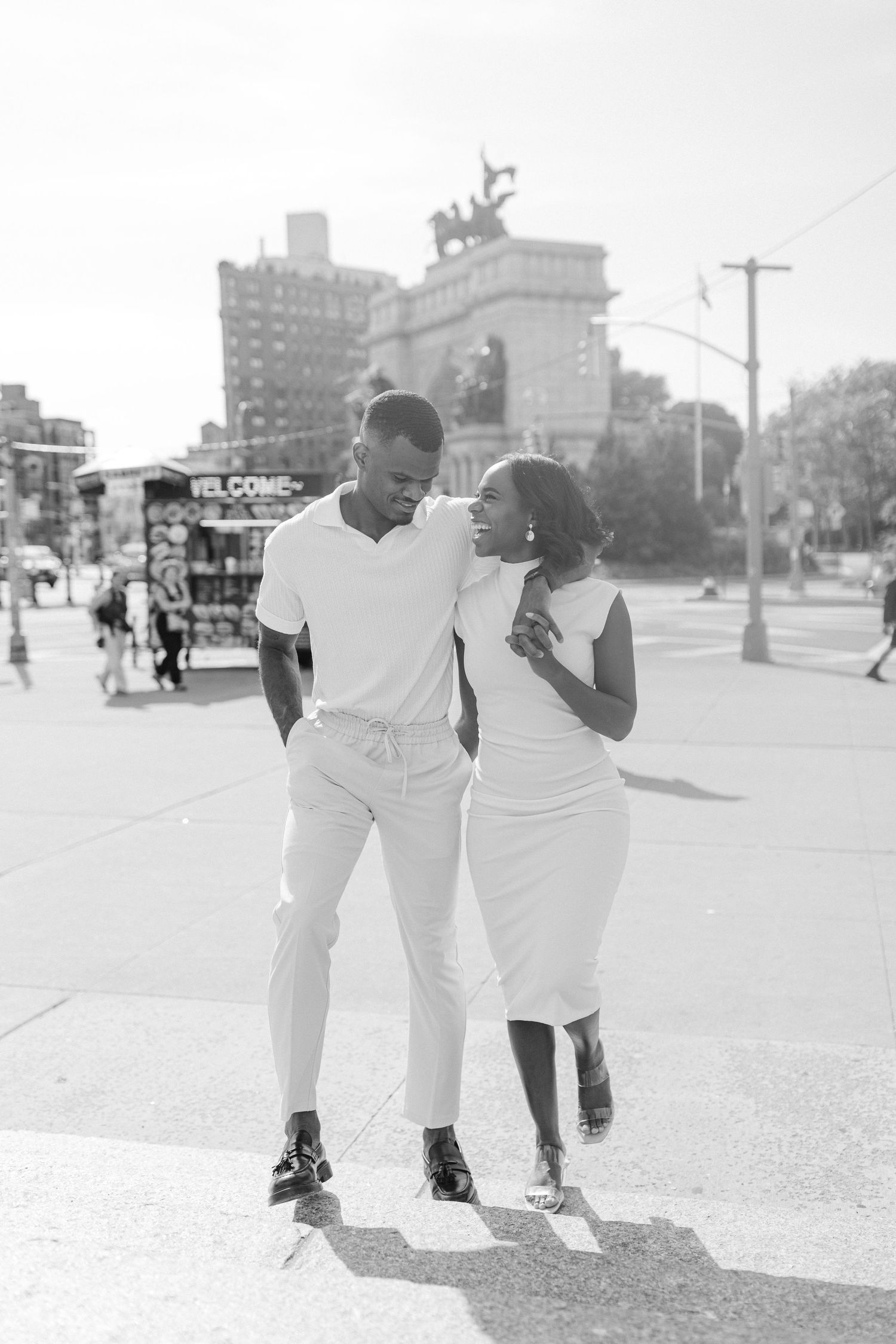 A couple in matching white outfits walking together near Grand Army Plaza in Brooklyn.